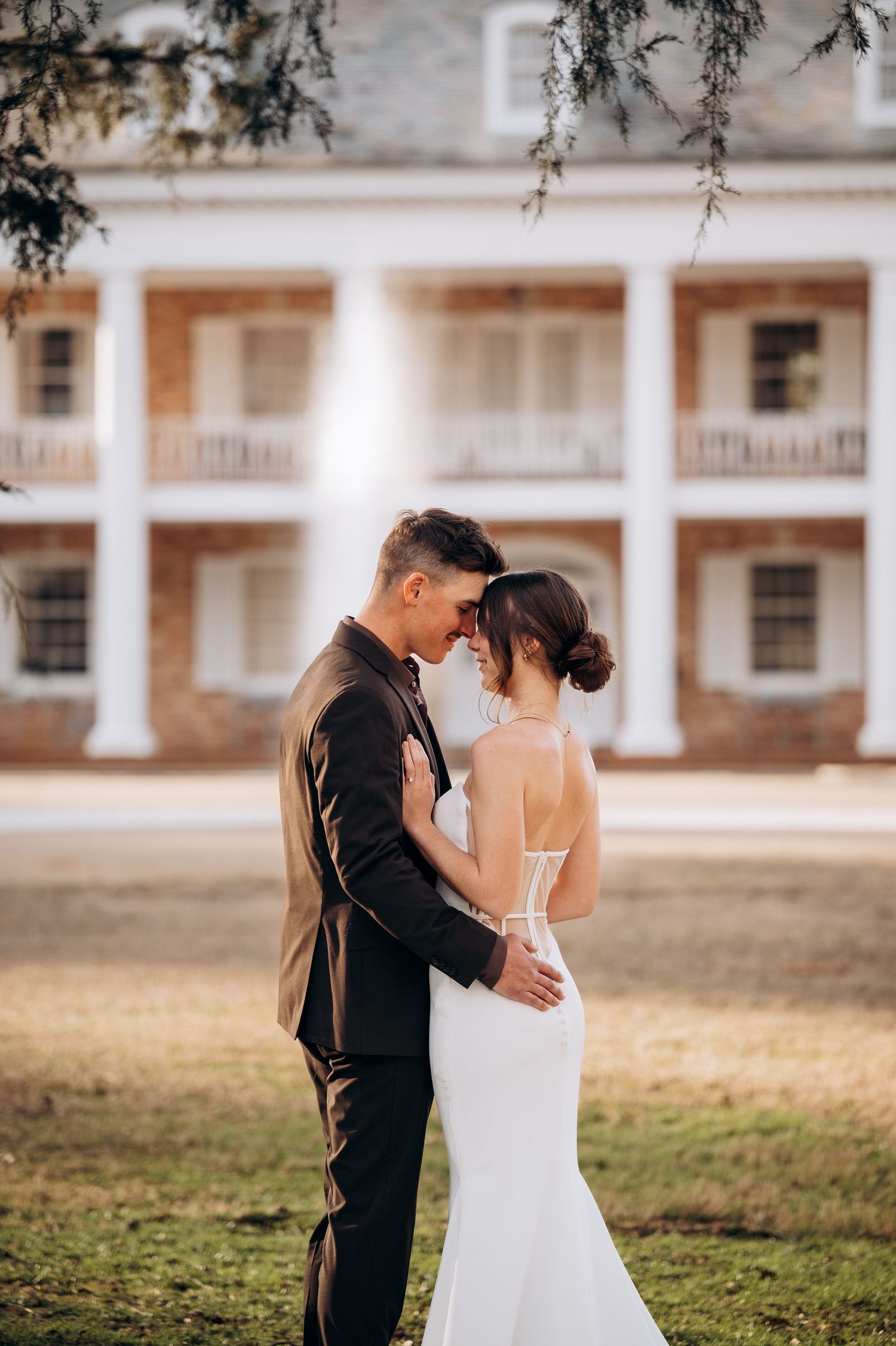A romantic outdoor wedding moment captured in front of a historic colonial style building.