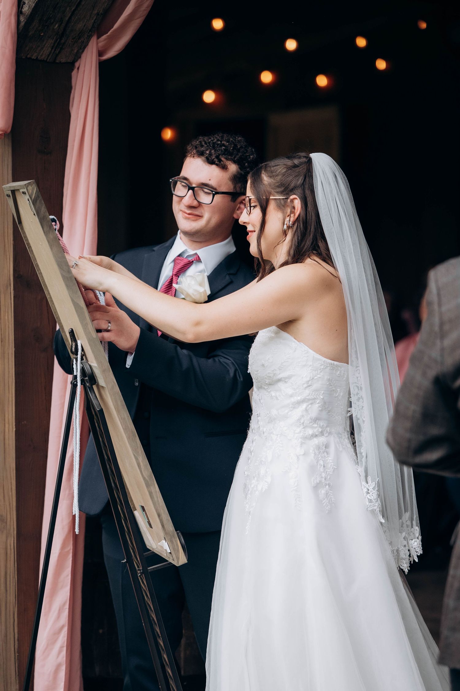 Couple shares intimate moment during wedding reception under string lights.