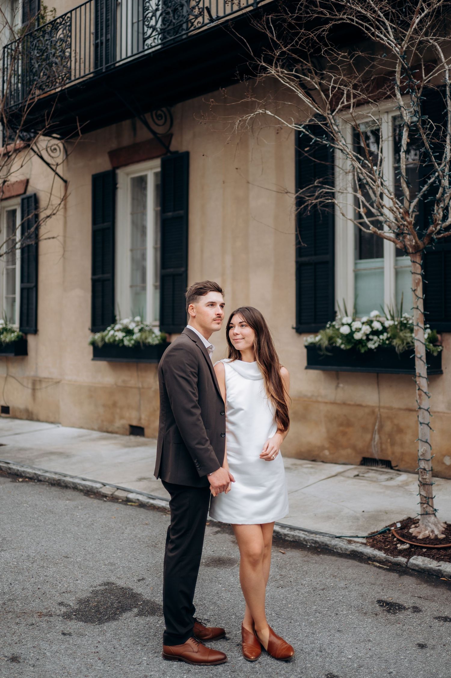 Romantic couple poses together on a charming historic street with brick buildings.