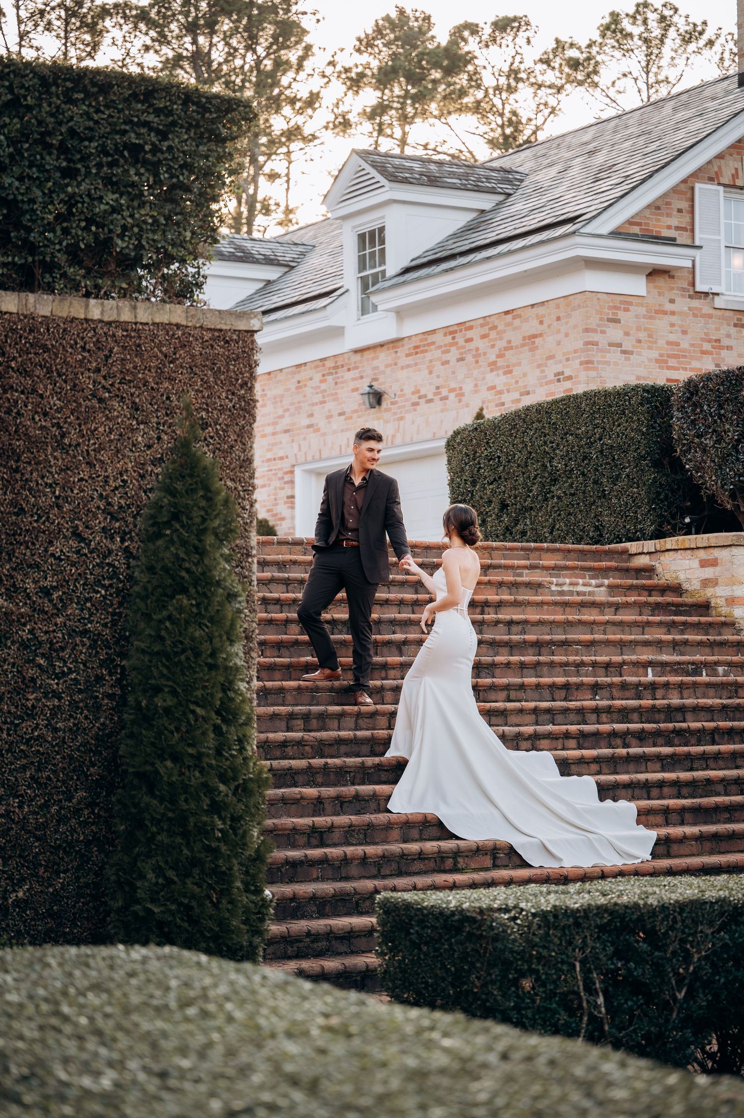 A romantic sequence of wedding photos captured on brick stairs surrounded by manicured hedges.