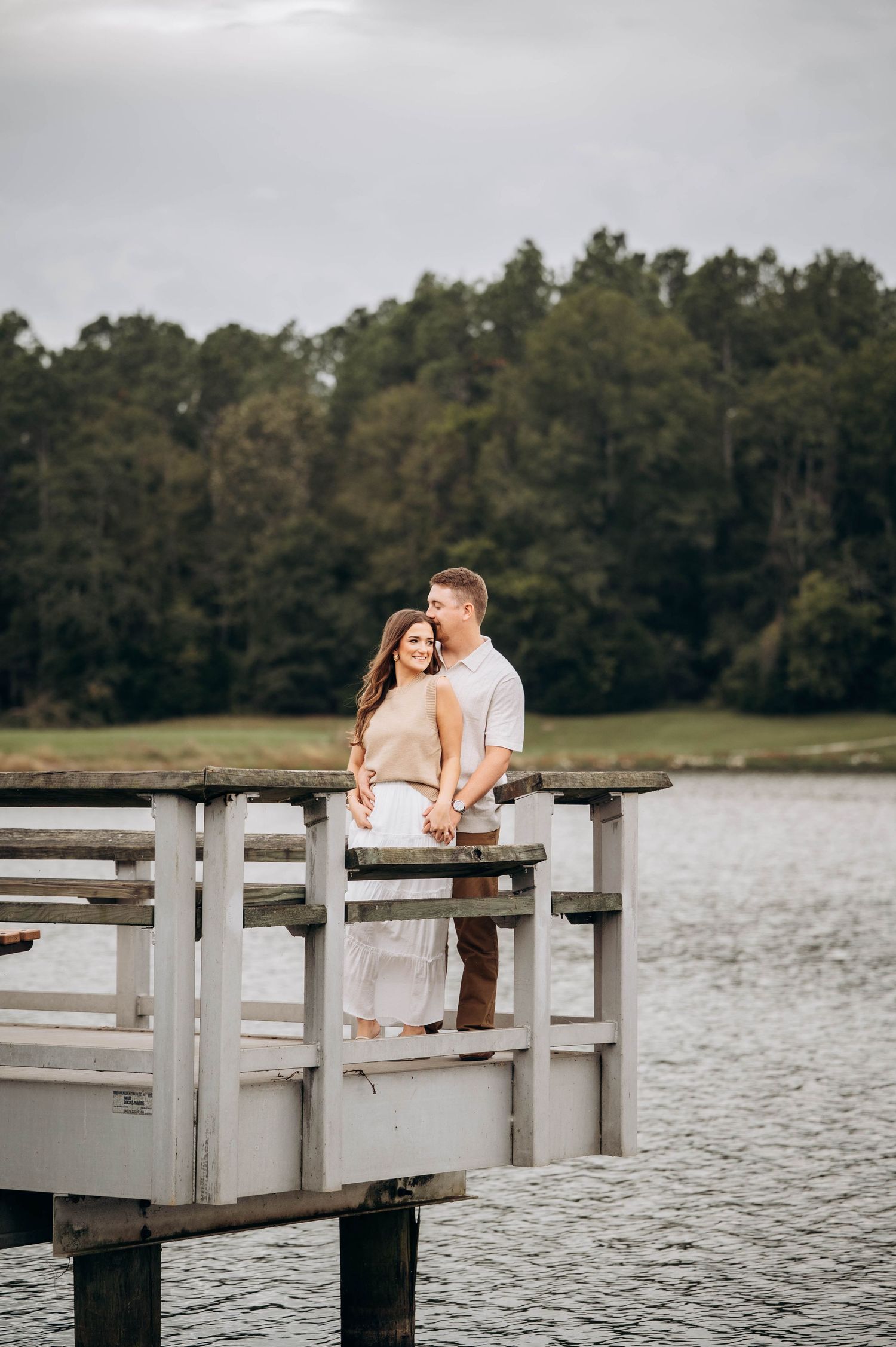 Romantic couple photos on wooden dock overlooking peaceful lake.