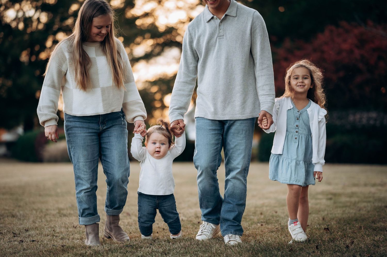 Family walking together on grass wearing coordinated casual outfits.
