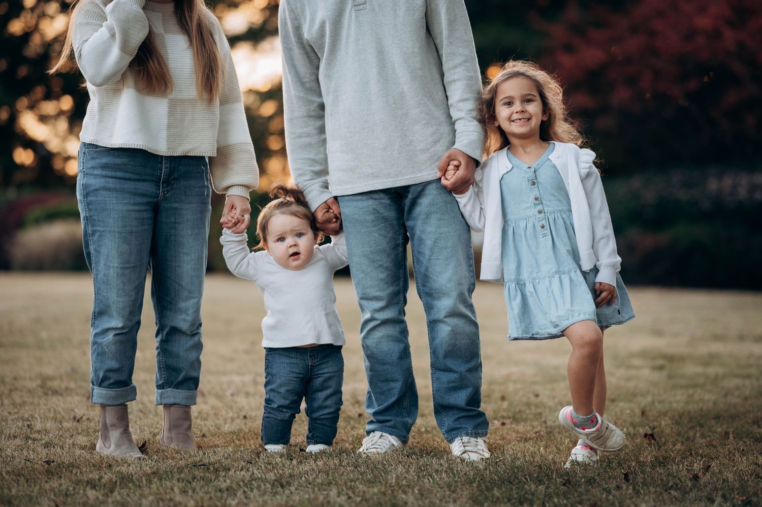 A family stands together outdoors wearing casual clothing in matching blue and white tones.