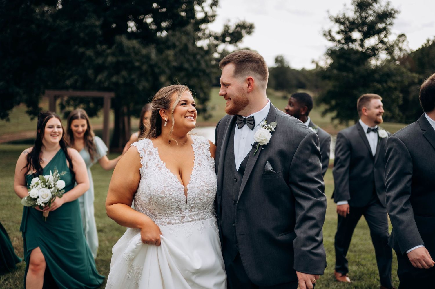 Wedding party members share candid moments during outdoor photo session.
