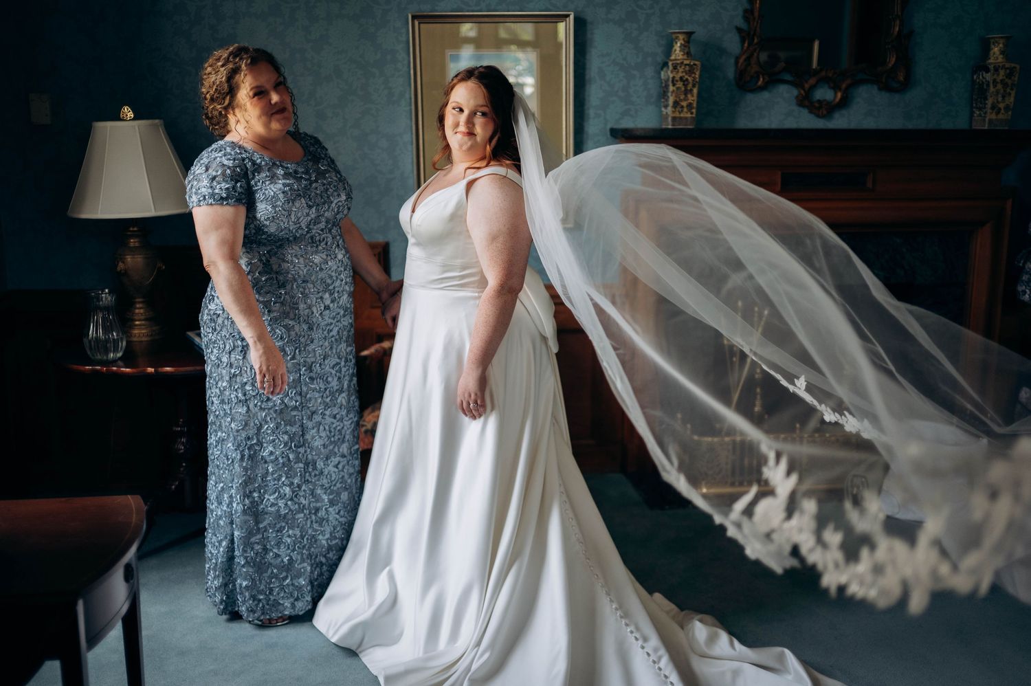 Wedding preparations with flowing white dress and veil in a dimly lit room.
