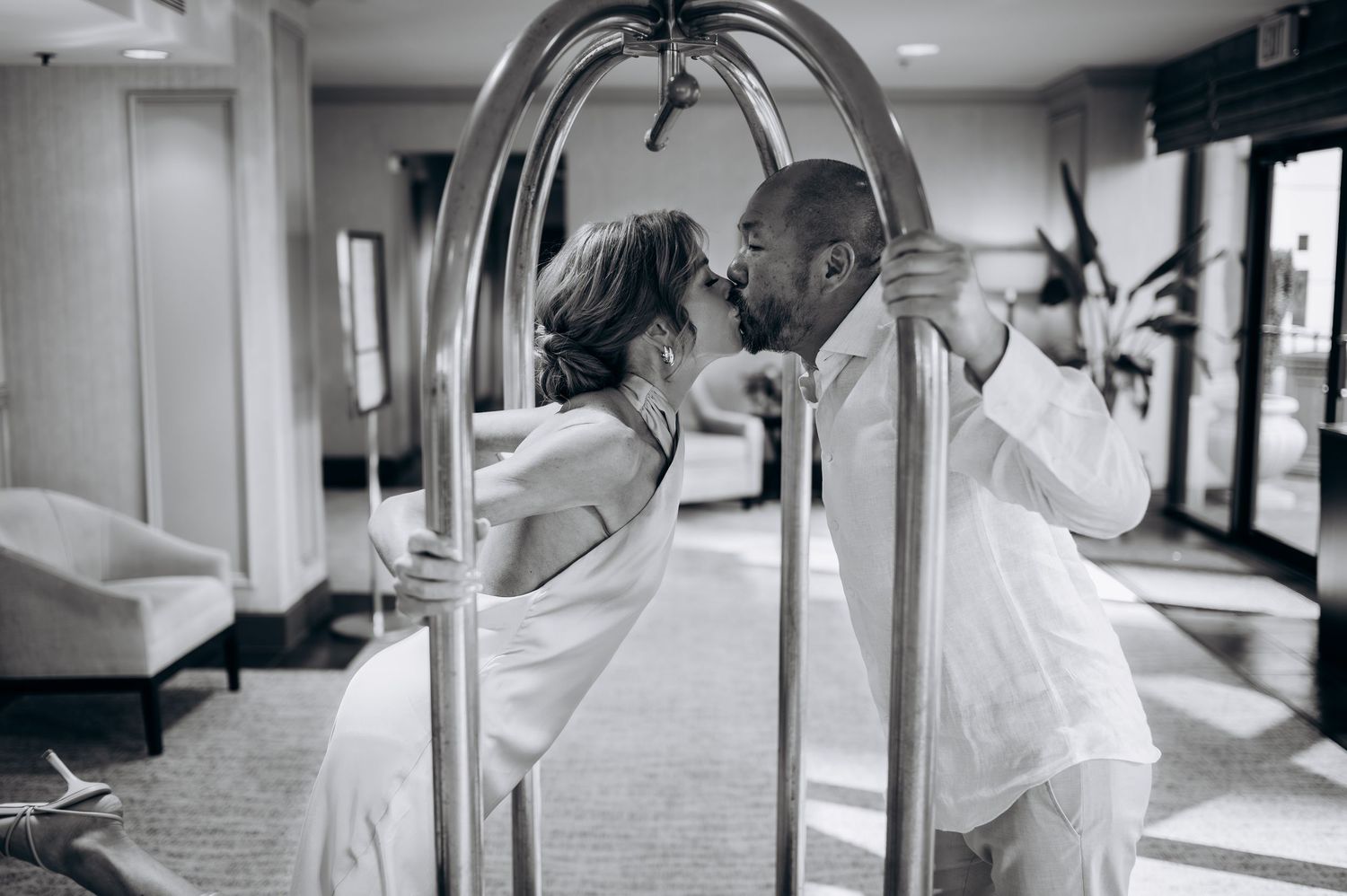 Romantic black and white image of couple kissing through decorative metal cart.
