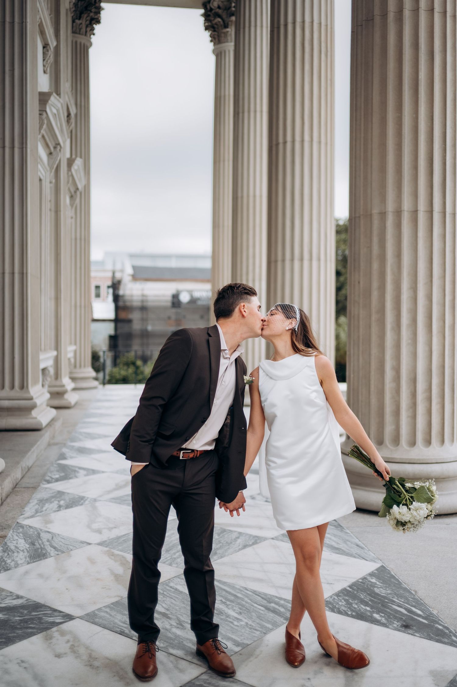 A romantic moment captured between a couple among classical white marble columns.