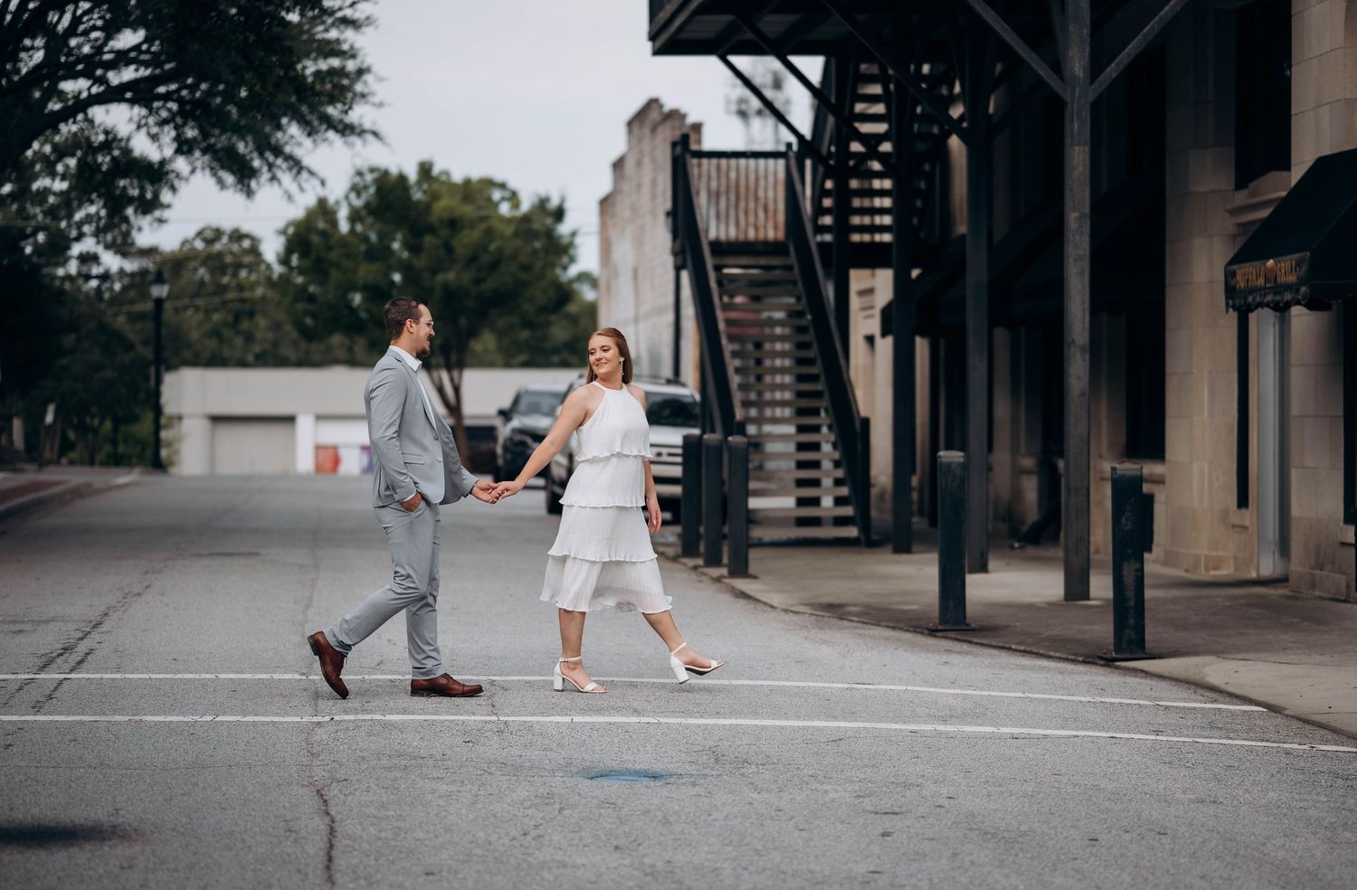 A couple walks together along an urban pathway near modern buildings.