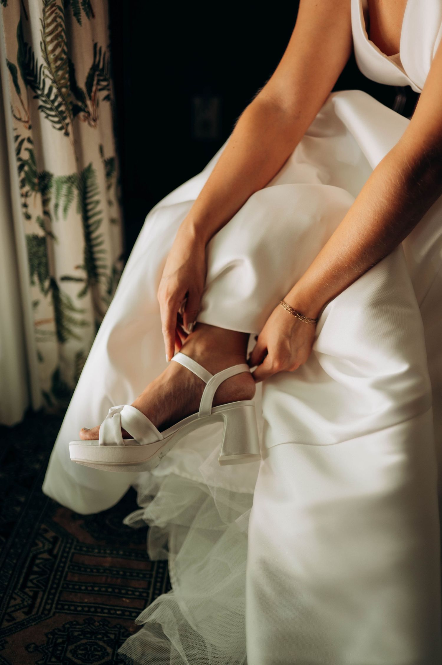 Close-up of bride's hands adjusting pockets in white wedding dress.