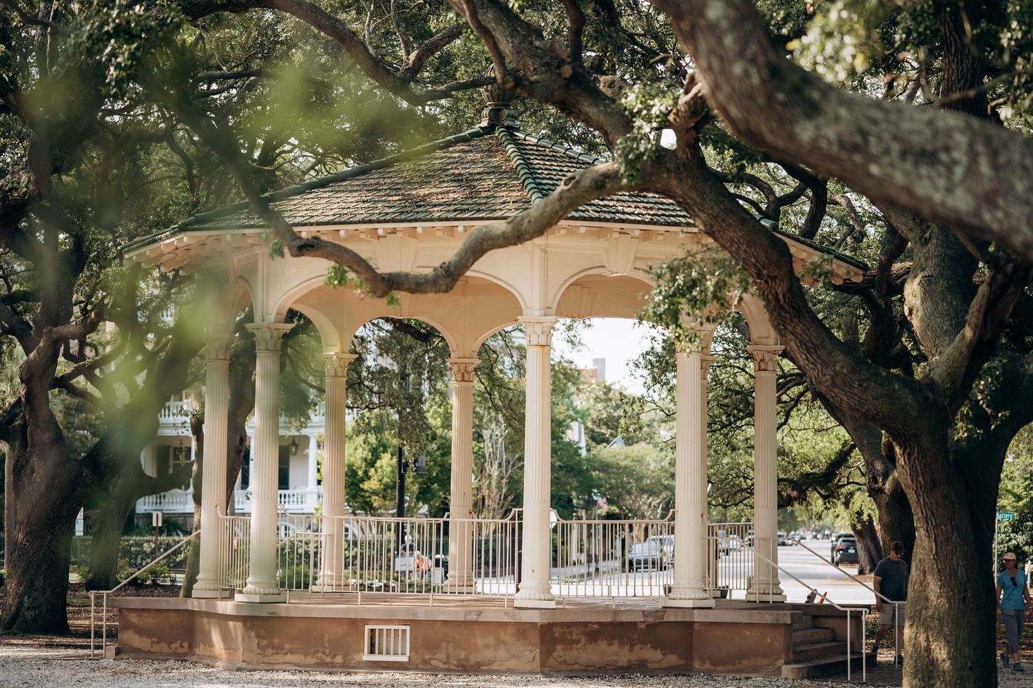 Elegant white gazebo with tall columns surrounded by sprawling oak trees in a serene Southern park setting.
