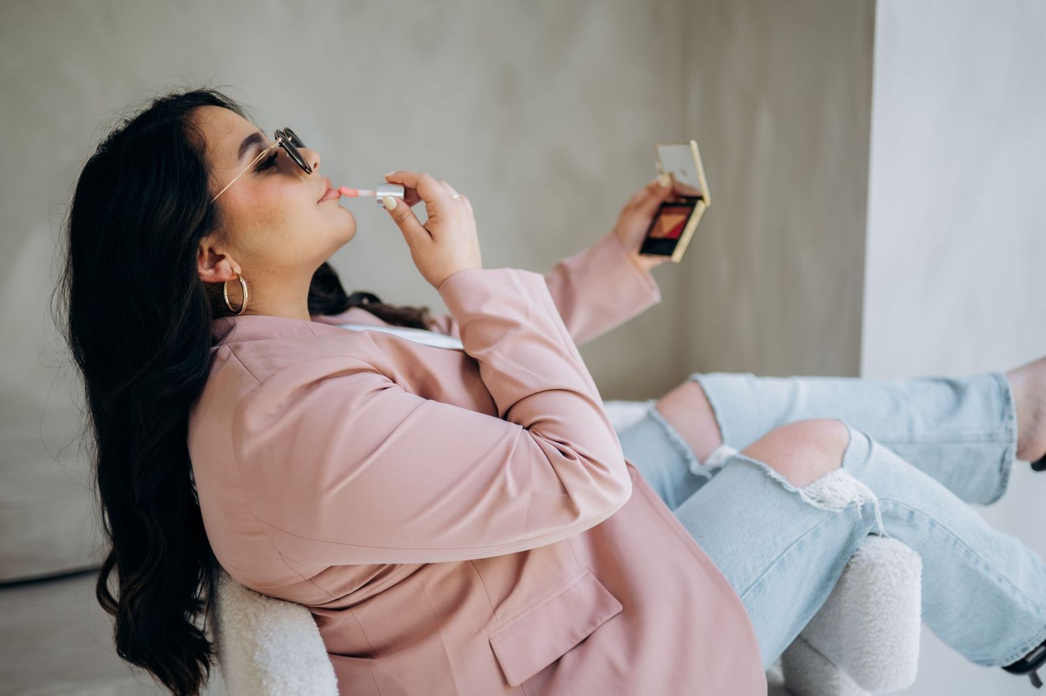 Woman in pink sweater relaxing on couch while enjoying snack and beverage at home.