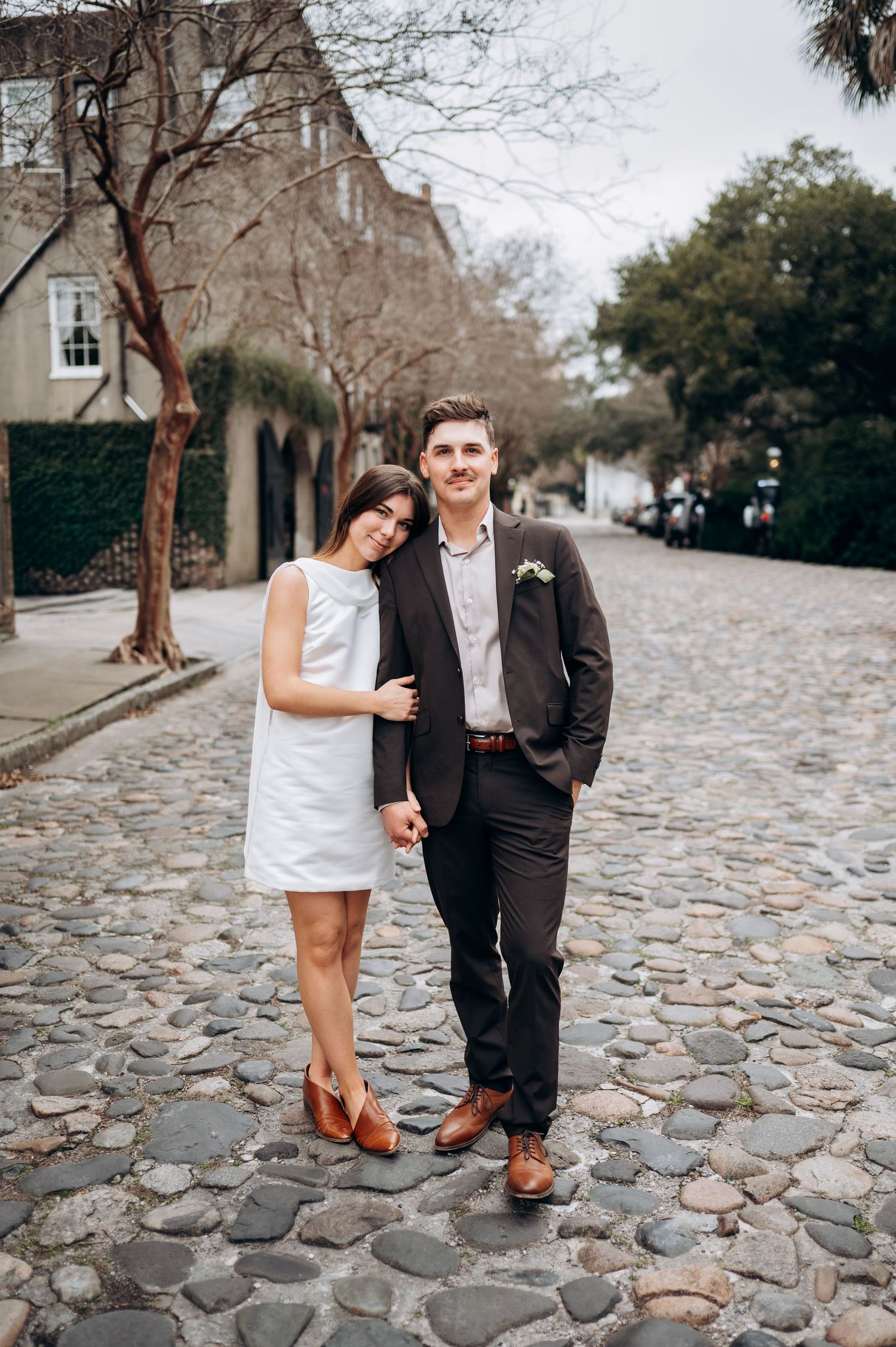 A couple playfully poses together on a historic cobblestone street.