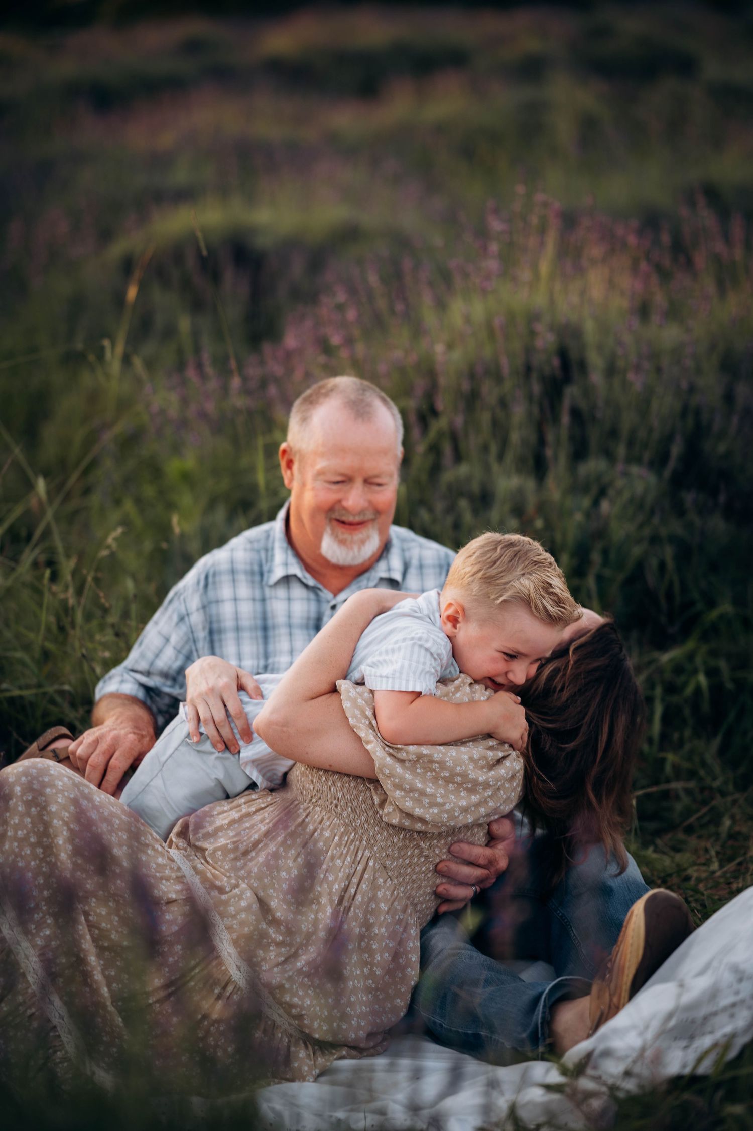 A heartwarming moment of laughter and joy captured in a field of tall grass at sunset.