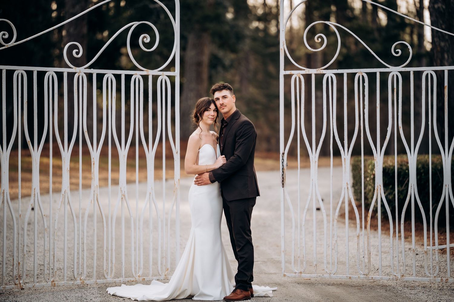 Romantic couple shares intimate moments along a decorative white iron fence.