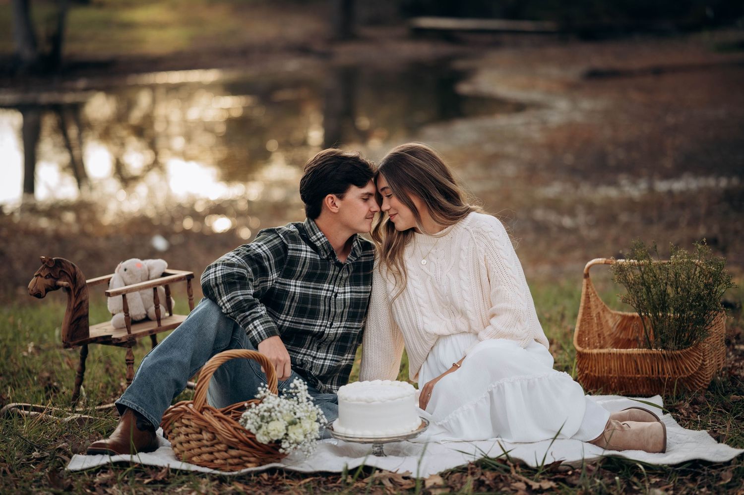 Couple enjoys romantic picnic on blanket with basket and flowers at sunset.