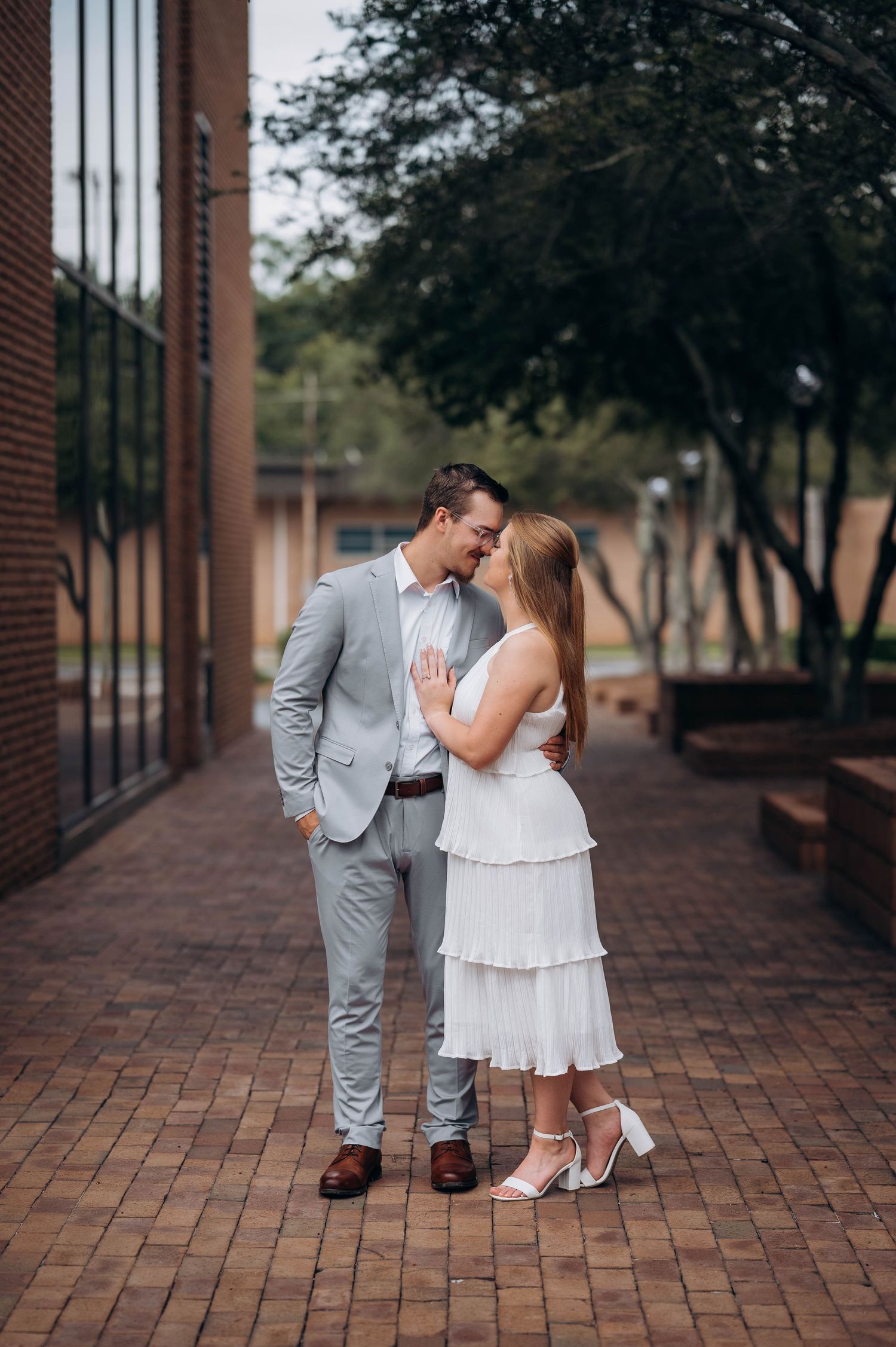 Romantic couple in formal wear sharing intimate moments on brick paved walkway.