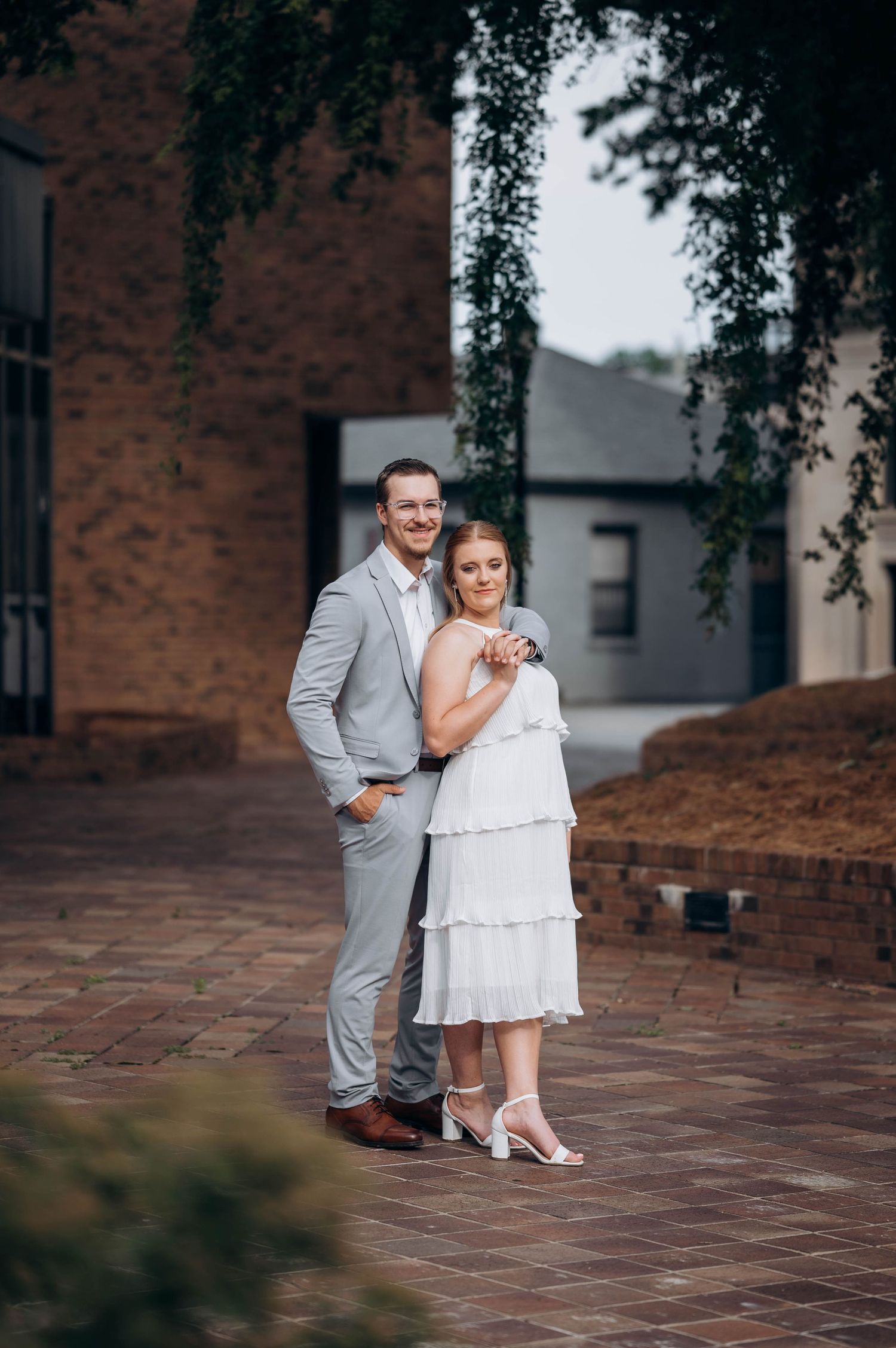 Couple in coordinated grey and white outfits posing on brick steps.