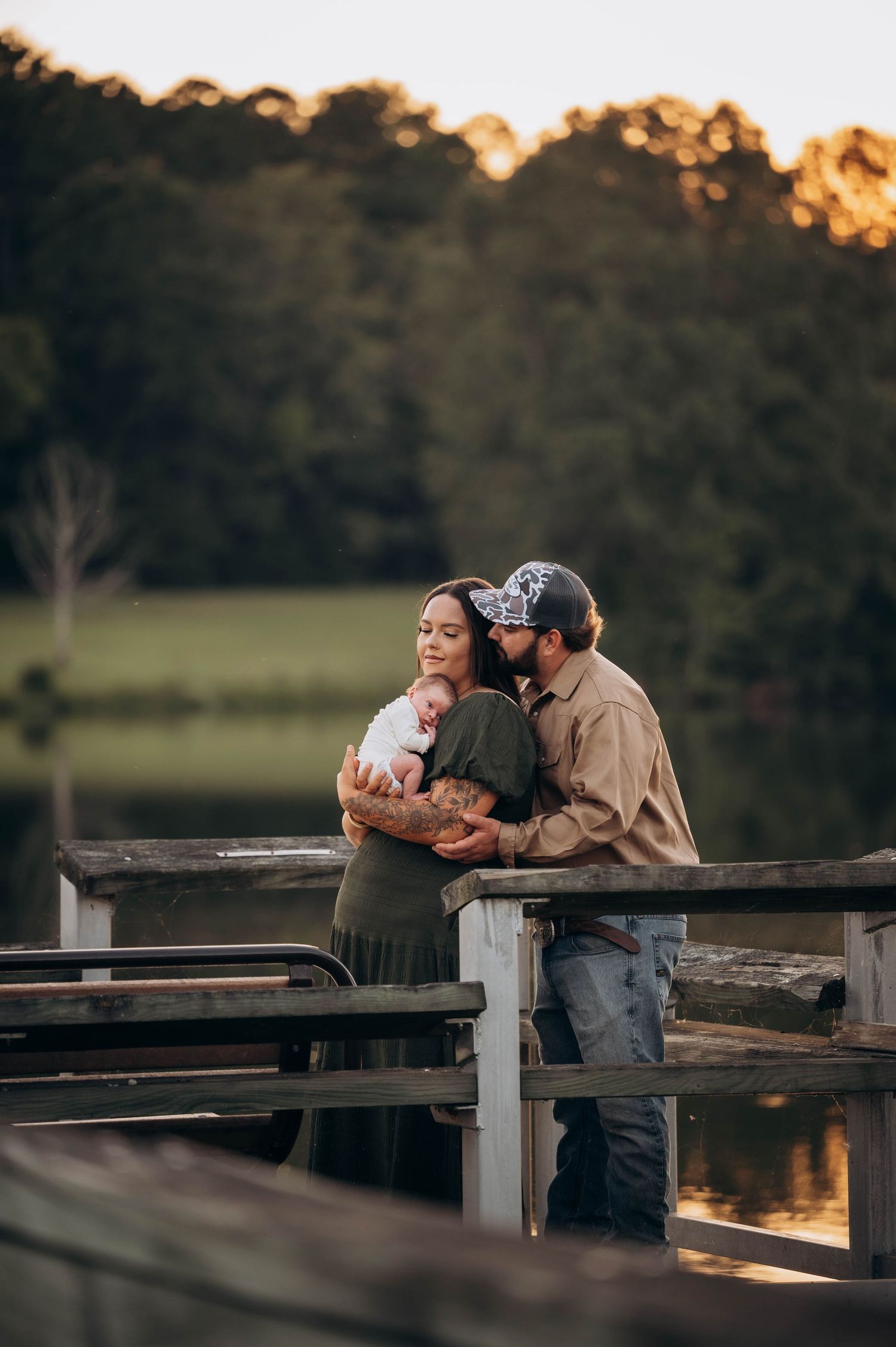 Loving family moment captured on lakeside dock during golden hour.