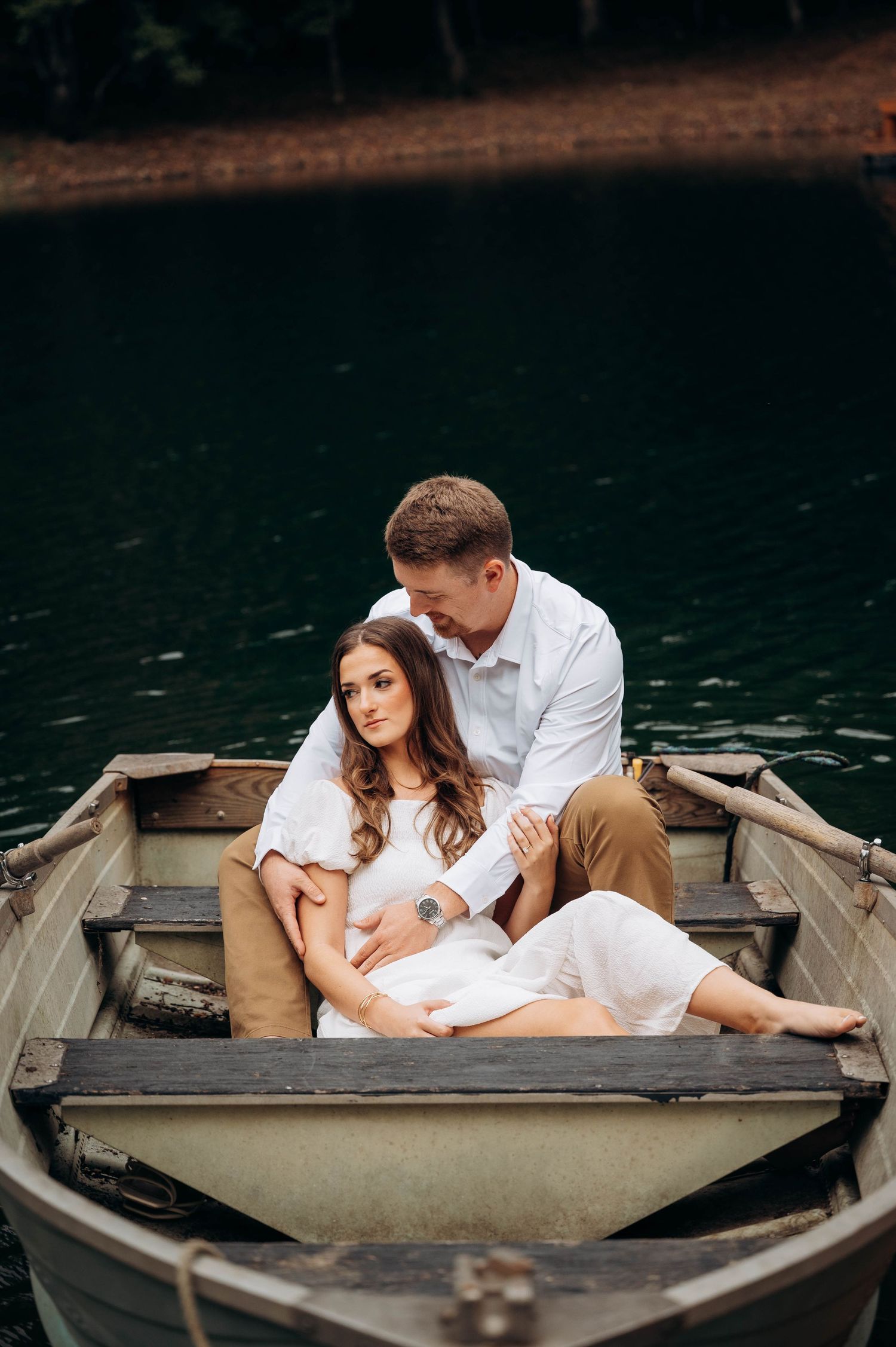 Couple lounges intimately in an aluminum boat floating on dark waters.