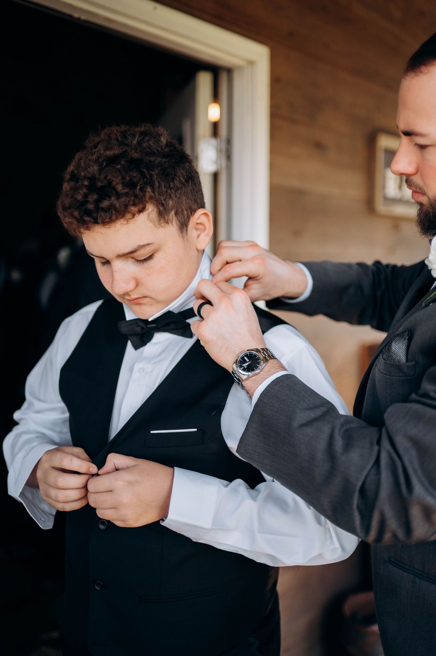 Groomsman adjusting his tie while getting ready in formal attire.