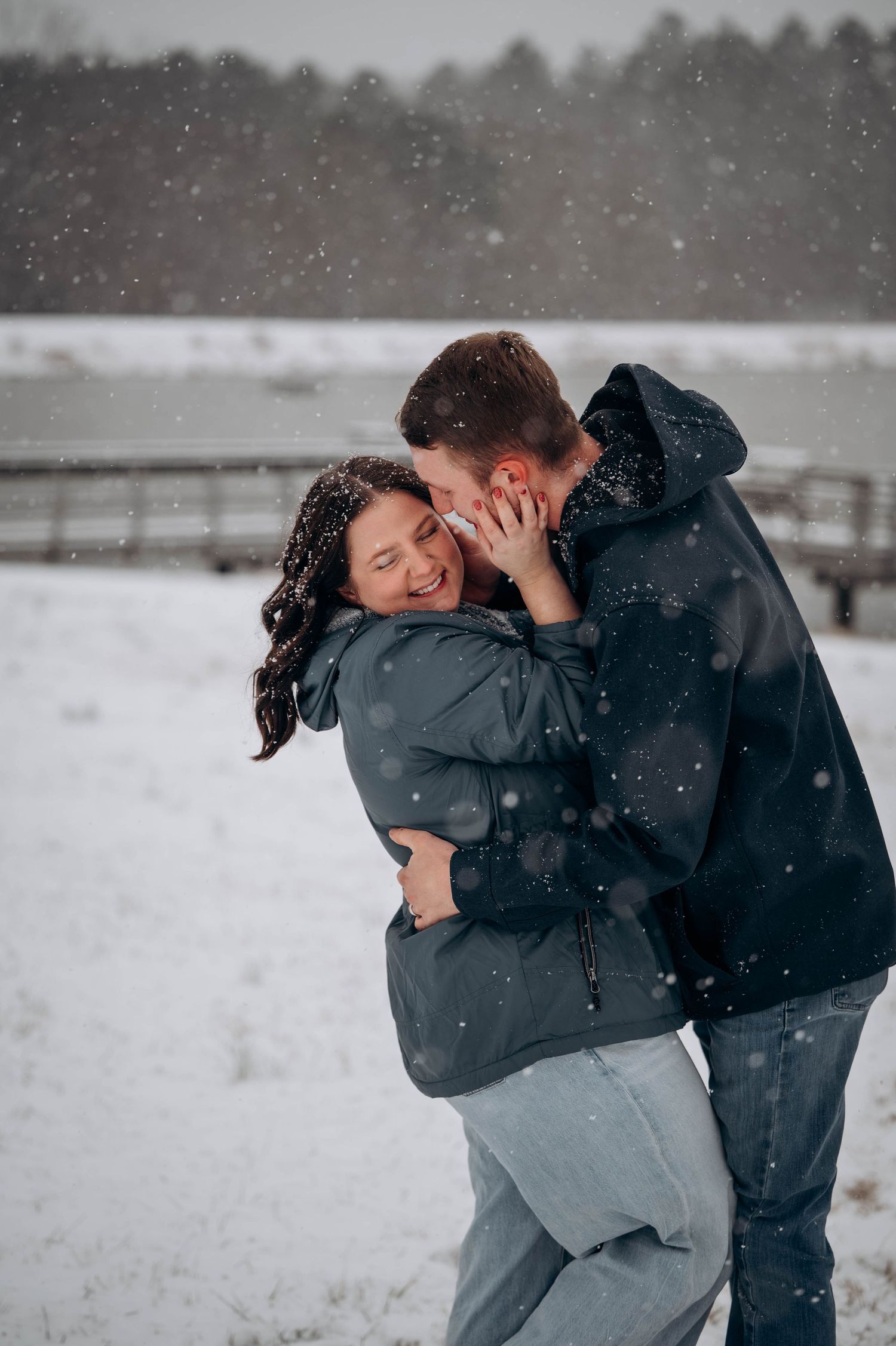 A couple shares intimate moments in a snowy winter landscape while wearing cozy outerwear.