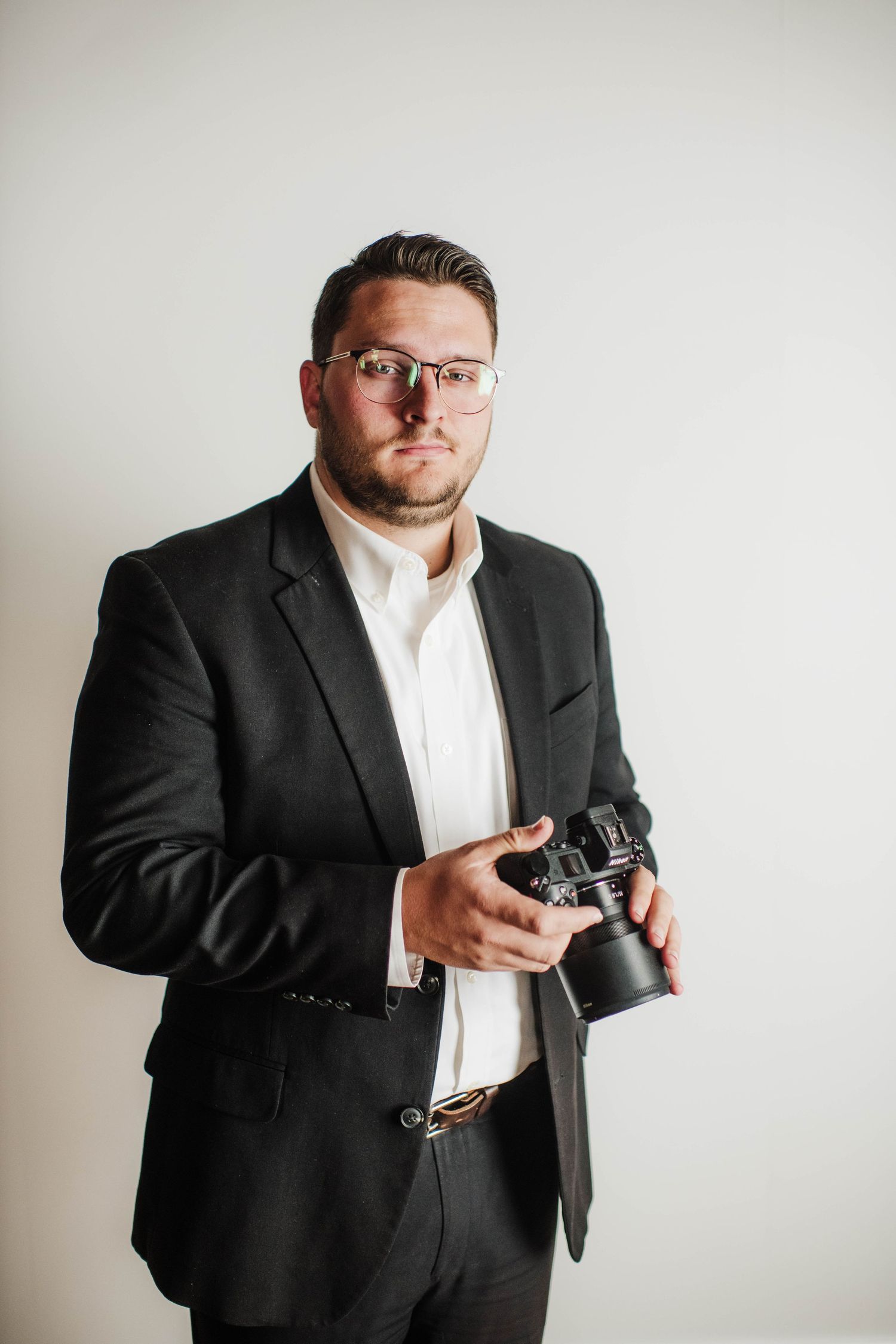 Professional photographer in suit demonstrates camera handling techniques in studio.