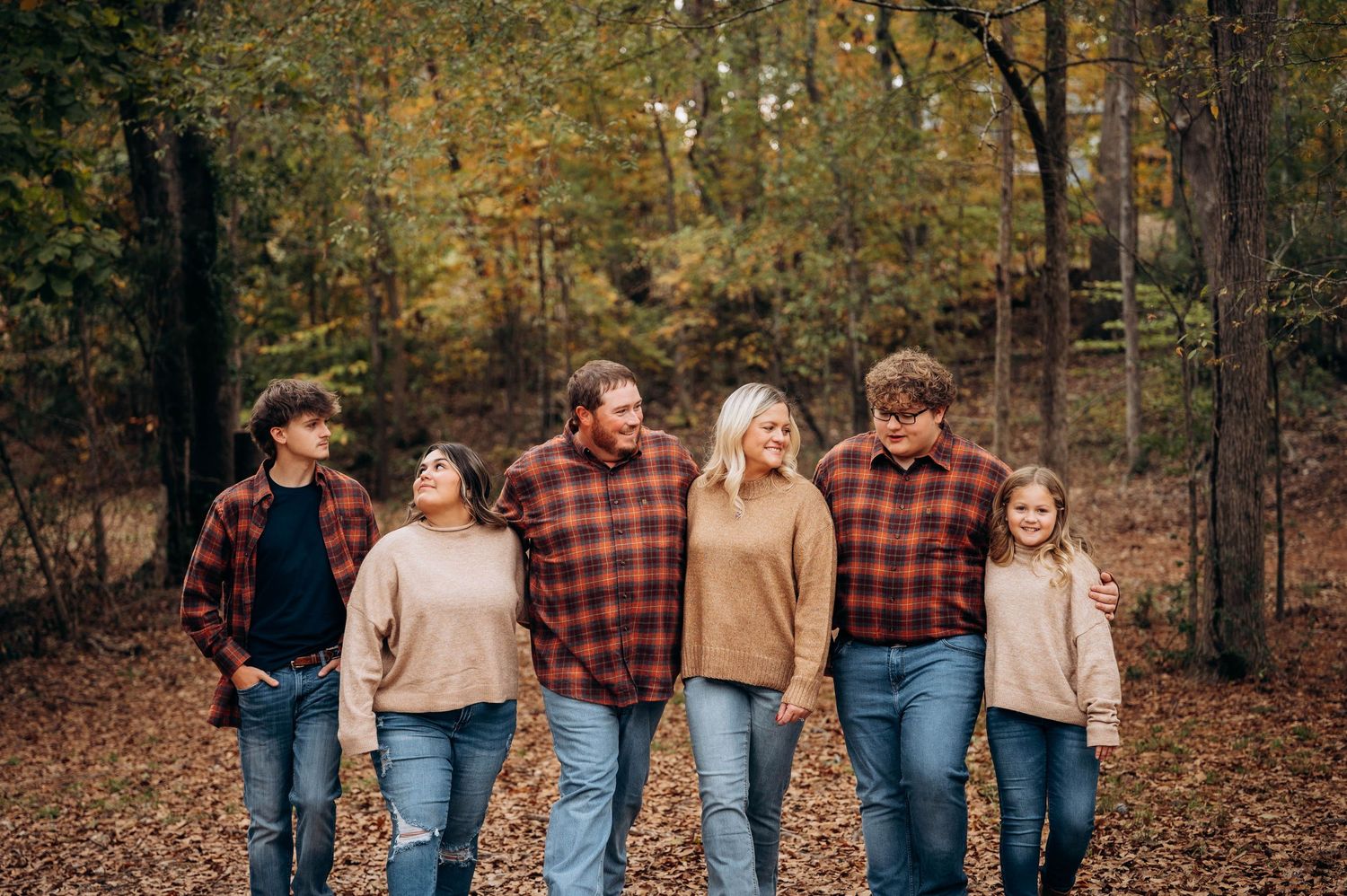Group walking together through autumn woods wearing coordinated casual outfits.