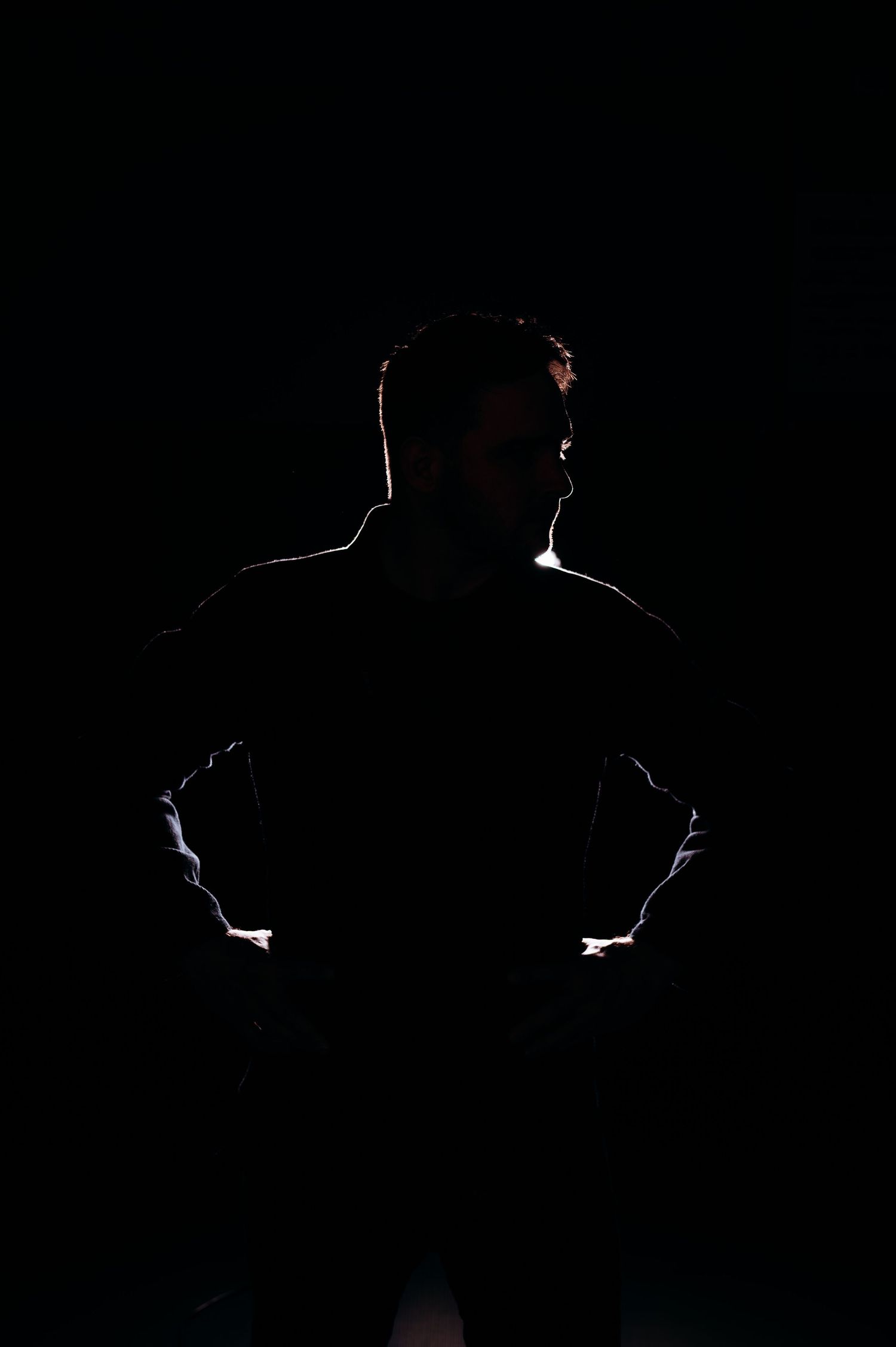 Silhouetted figure in athletic wear creates dramatic contrast against dark background.