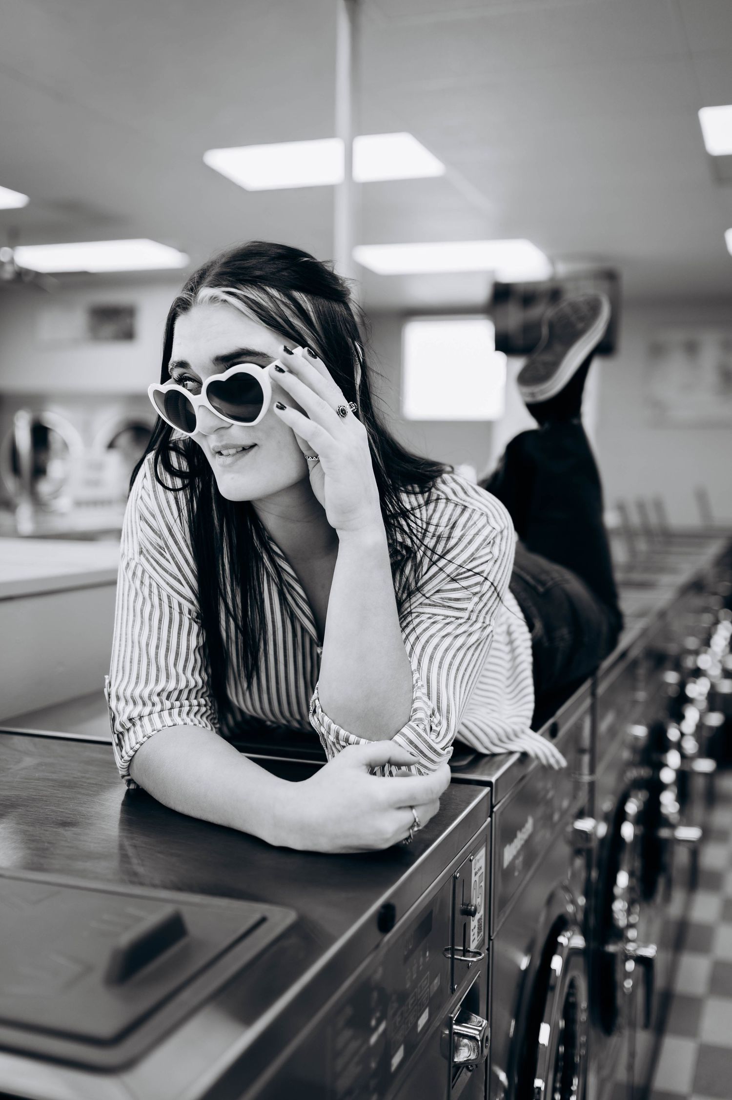 Black and white photo of someone in striped shirt and sunglasses leaning on counter in retro diner setting.