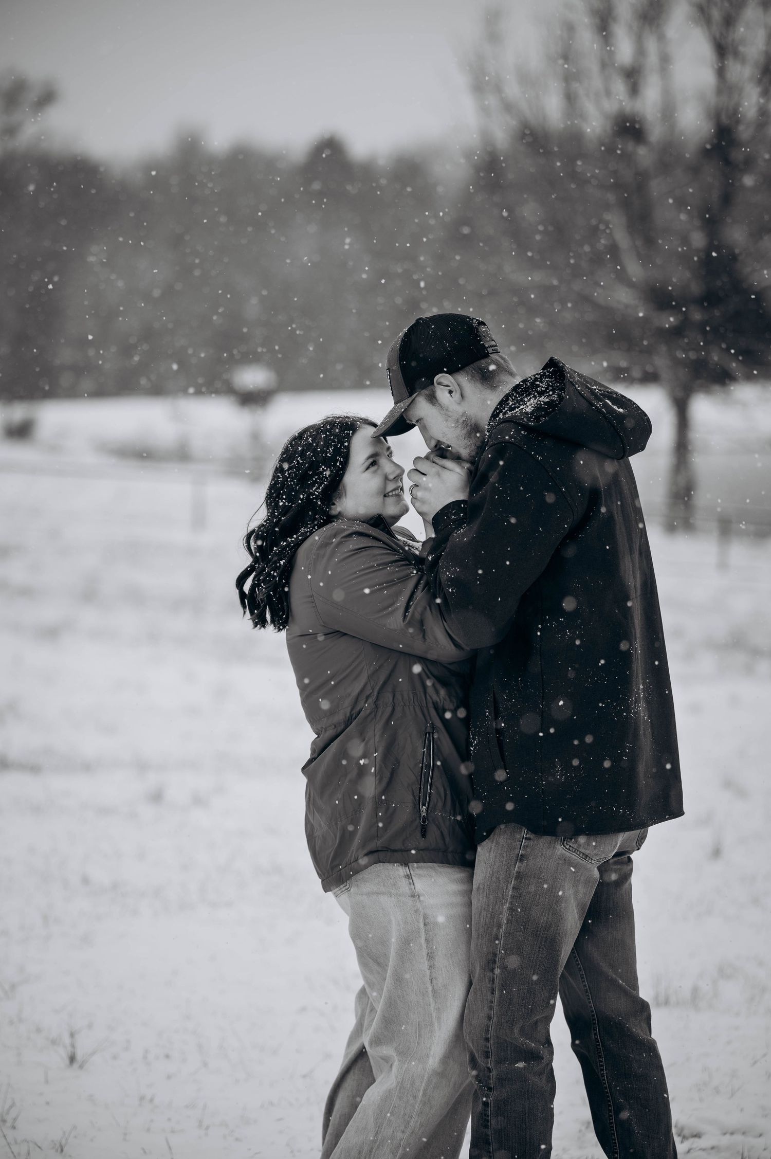 A tender moment captured between two people during snowfall in a serene winter landscape.