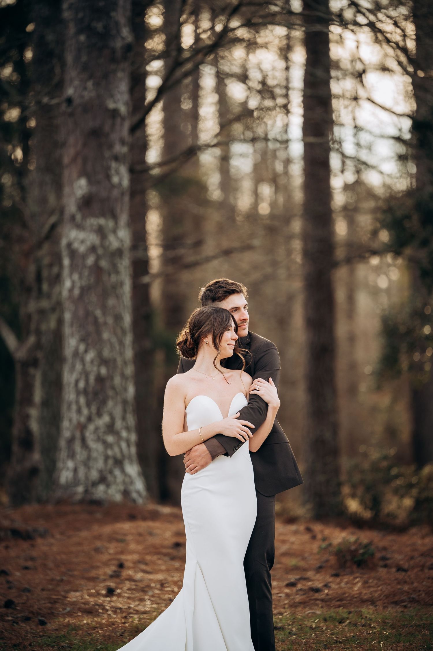 Couple in wedding attire sharing intimate dance in autumn forest setting.