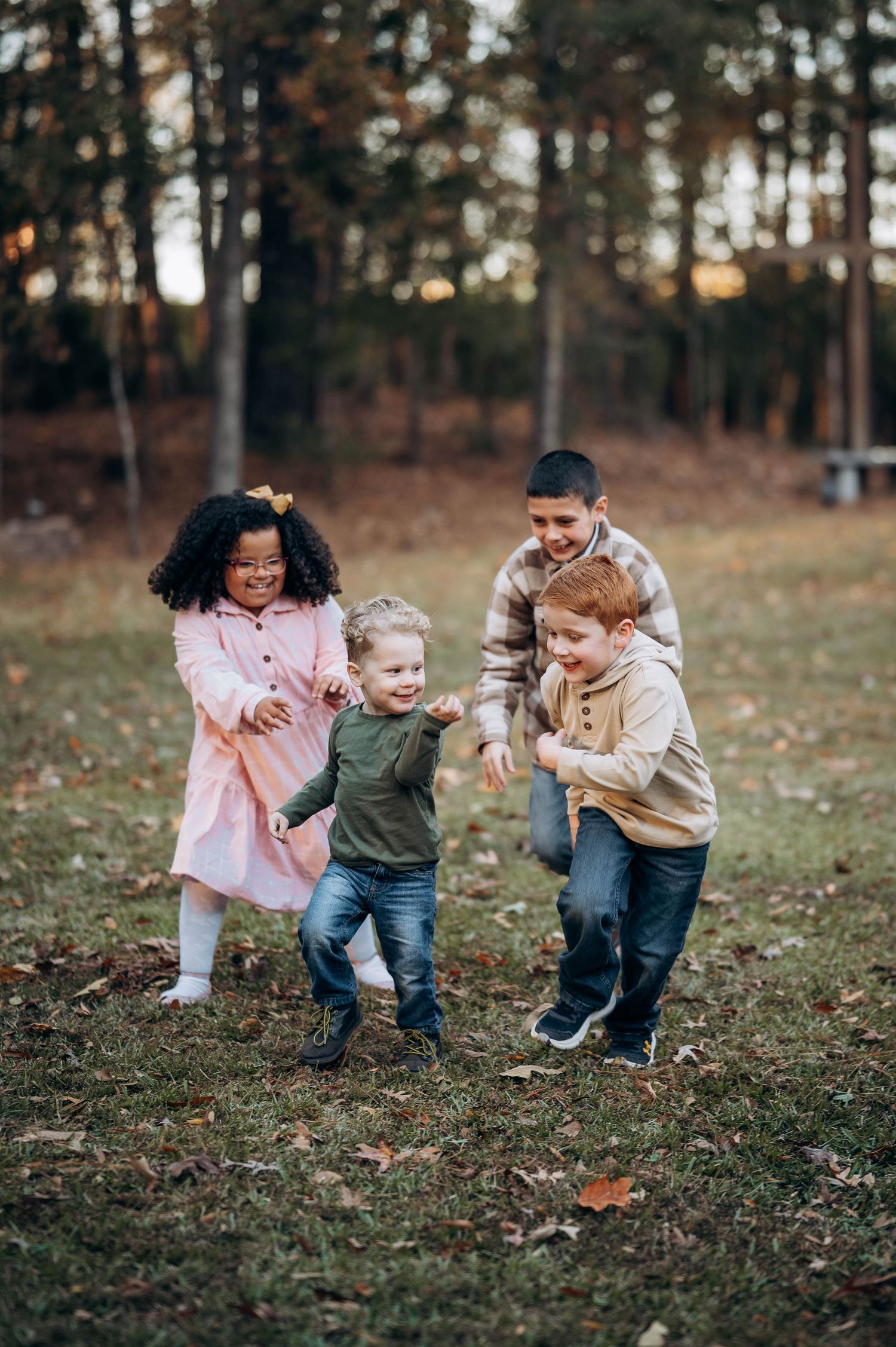 Children playing and running together on grass during a fall day.