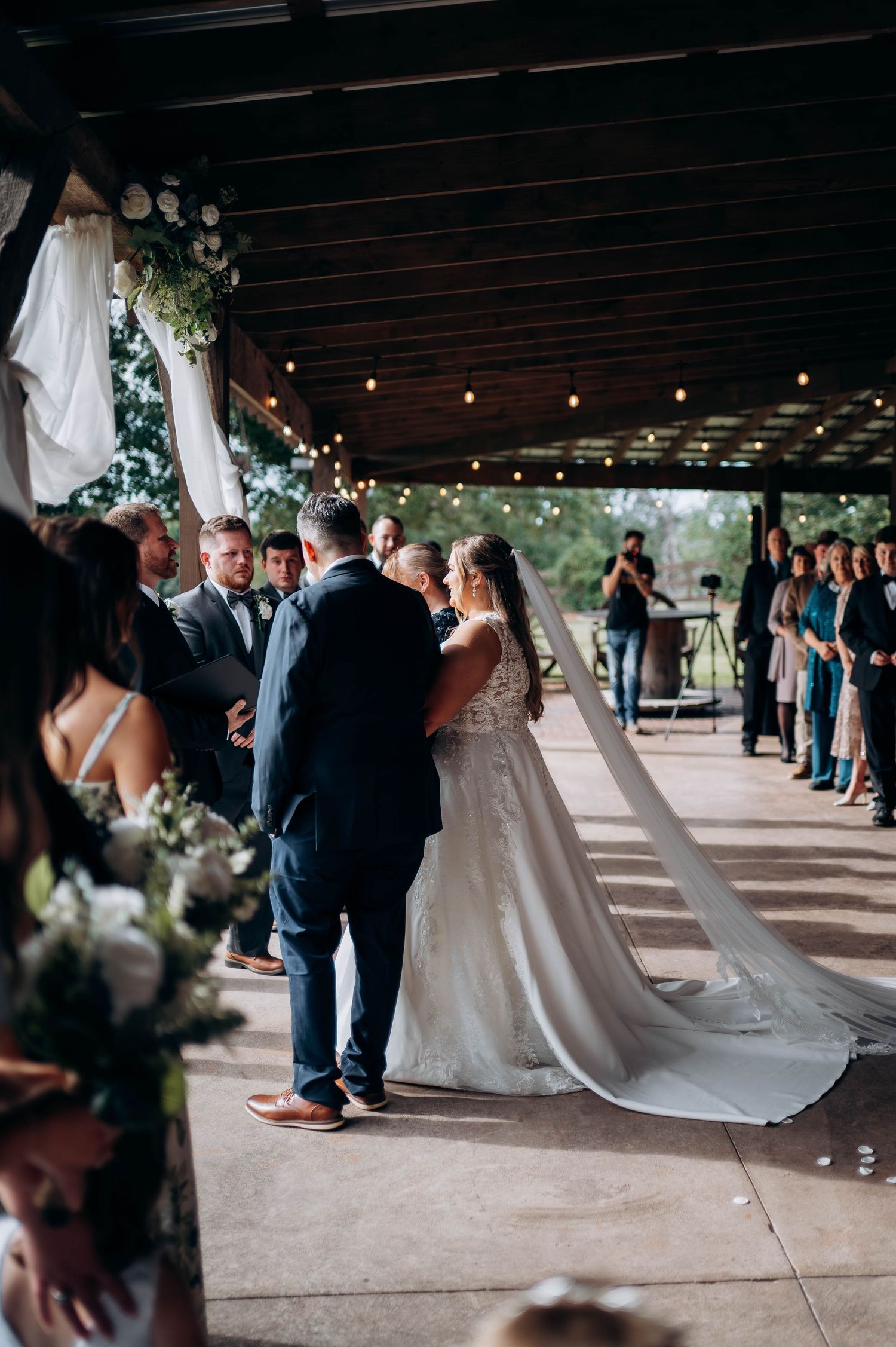 Wedding ceremony processional under covered outdoor venue with string lights.