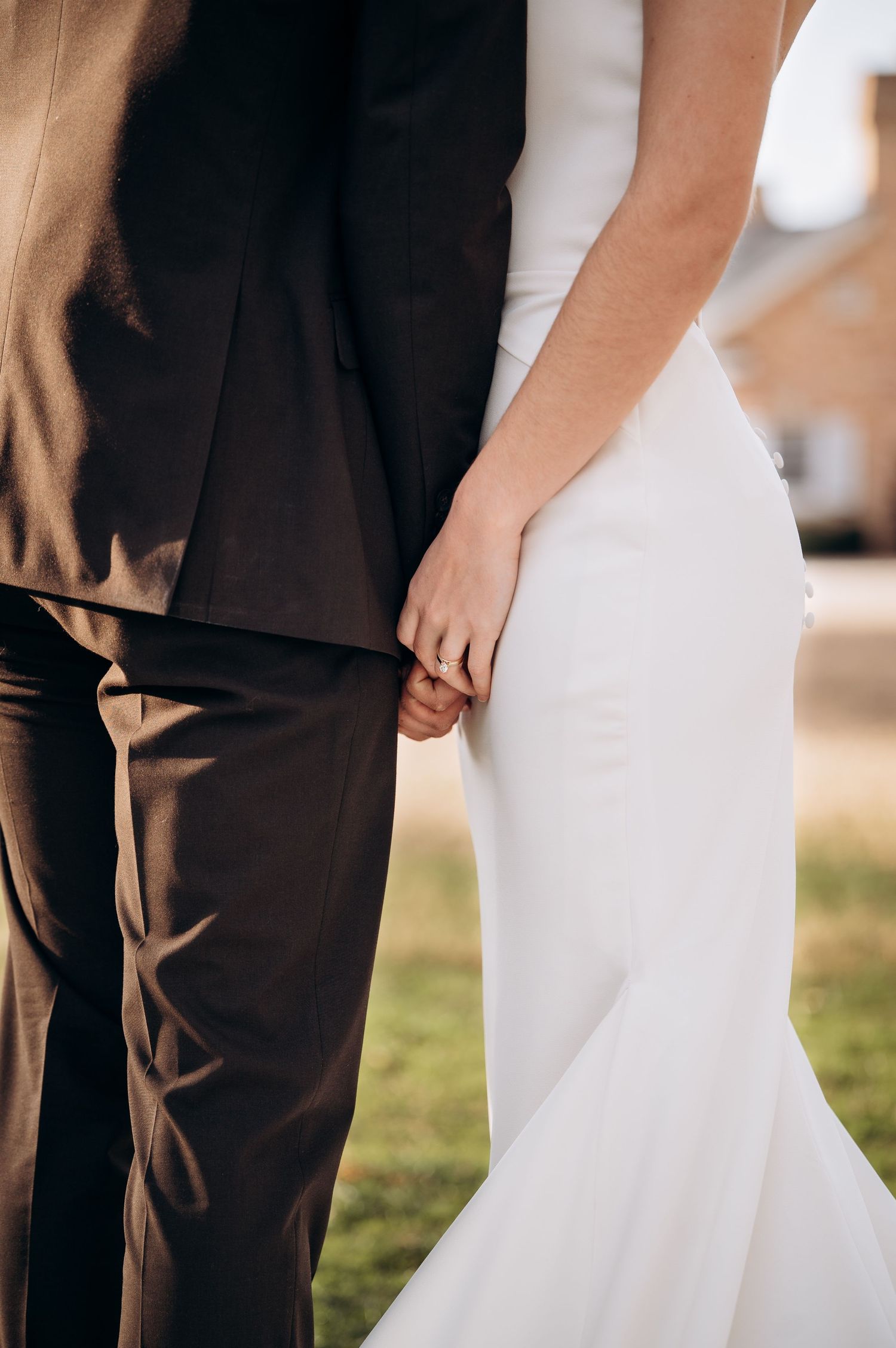 Close-up detail of wedding attire showing white mermaid dress against dark suit.