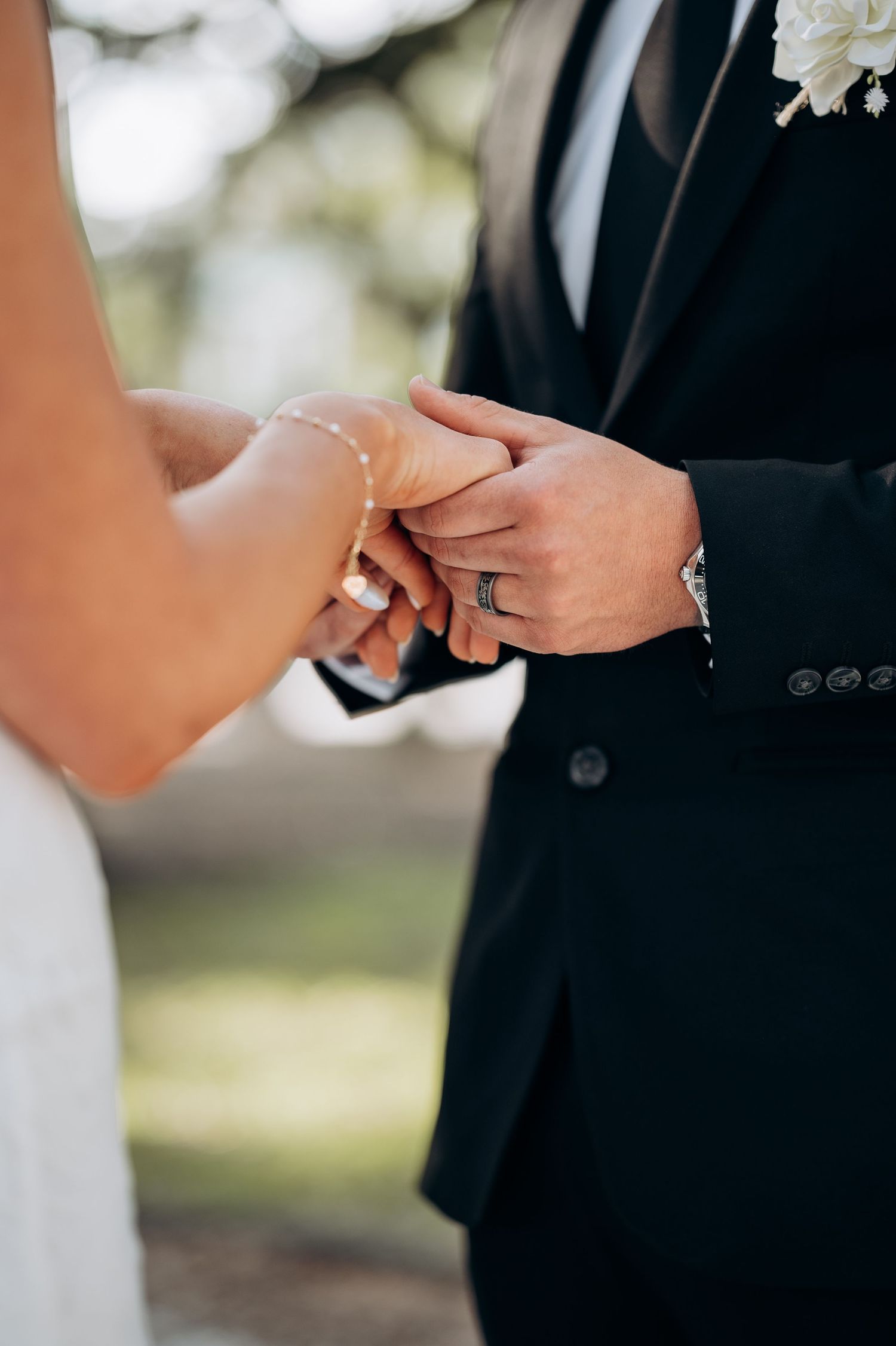 Close-up of bride and groom exchanging rings during outdoor wedding ceremony.