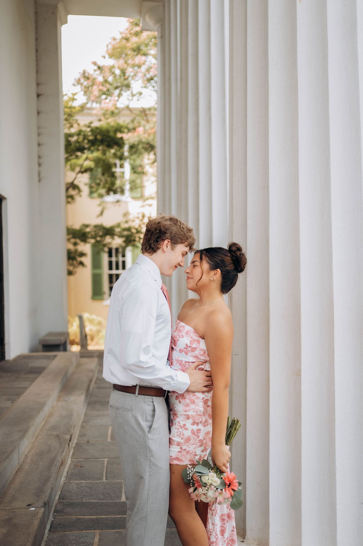 Couple sharing a romantic moment between white classical columns.