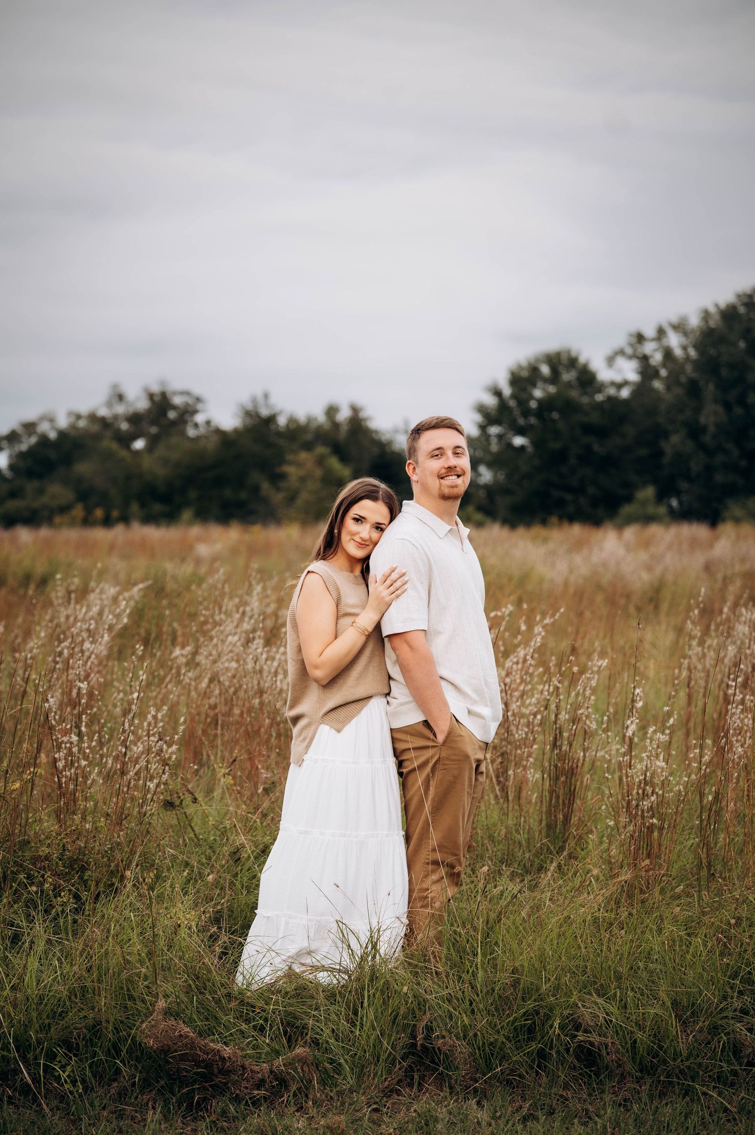Playful couple shares joyful moments in an outdoor field with natural lighting.