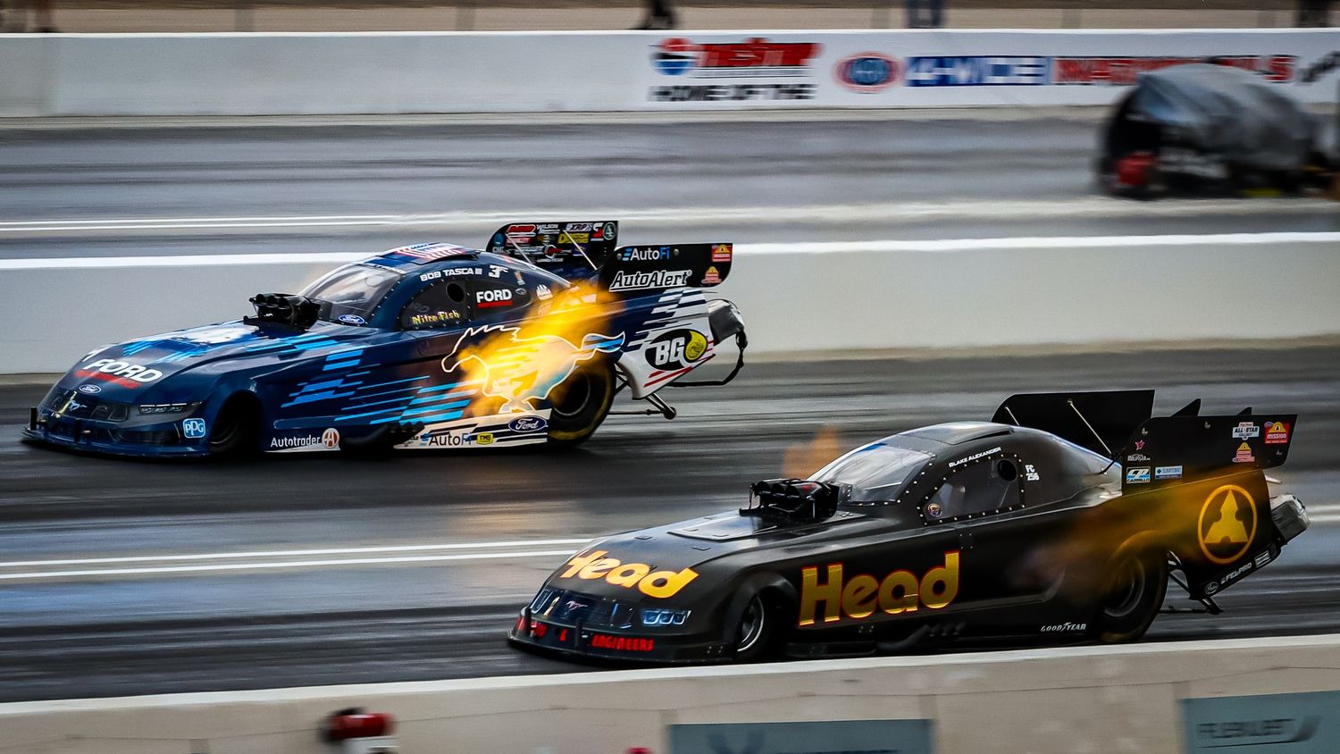 Multiple dragsters racing side by side on a professional drag strip.