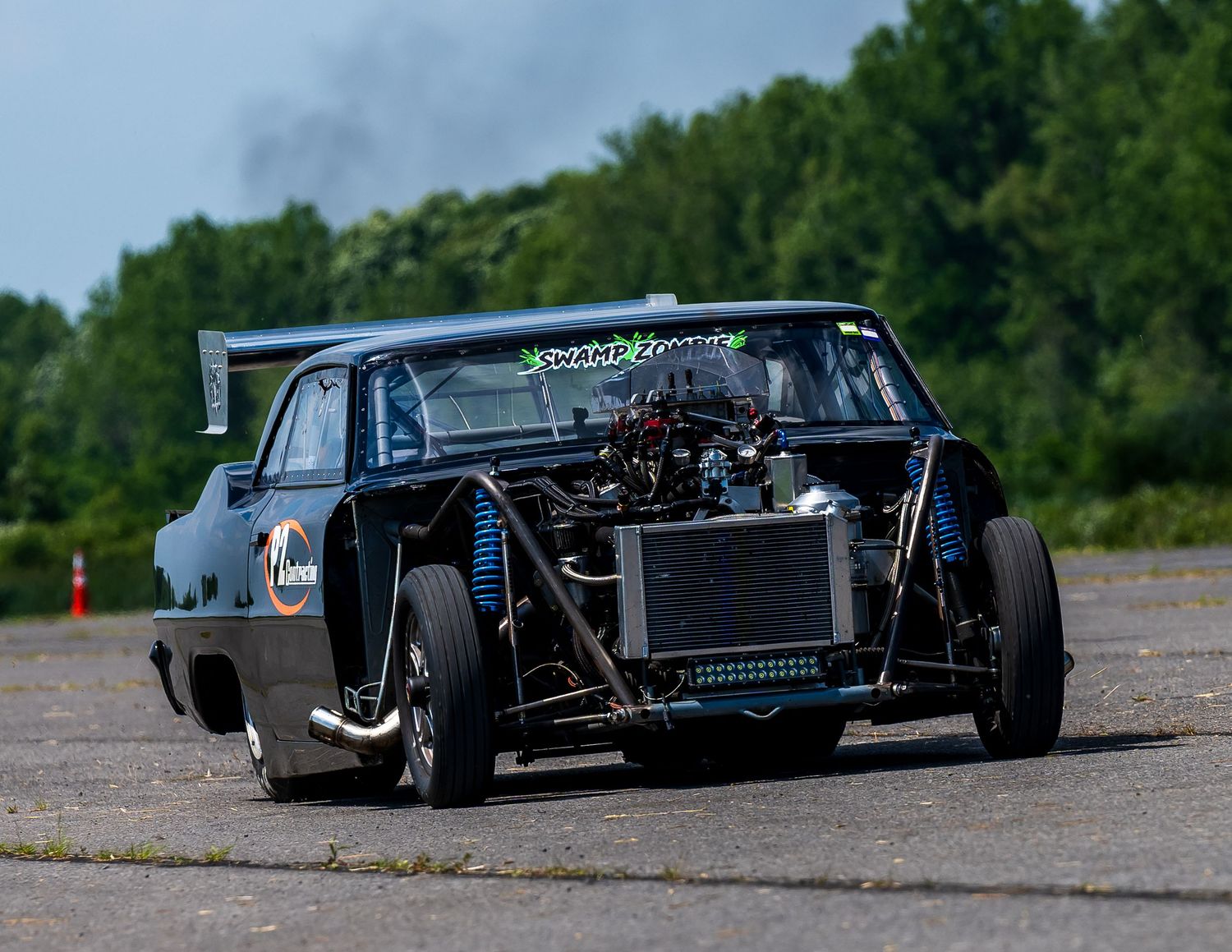 Row of custom black race cars lined up on asphalt track.