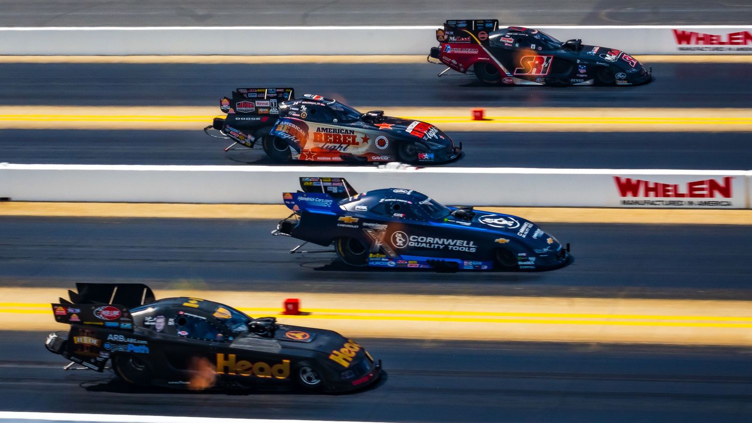 Drag racing competition featuring multiple high-powered vehicles on track.