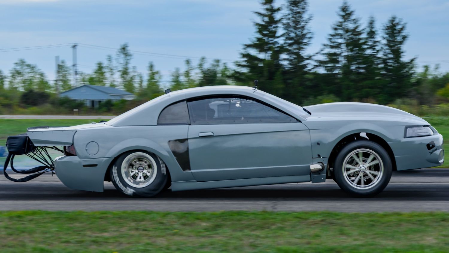 Silver sports cars racing side by side on a professional drag racing track.