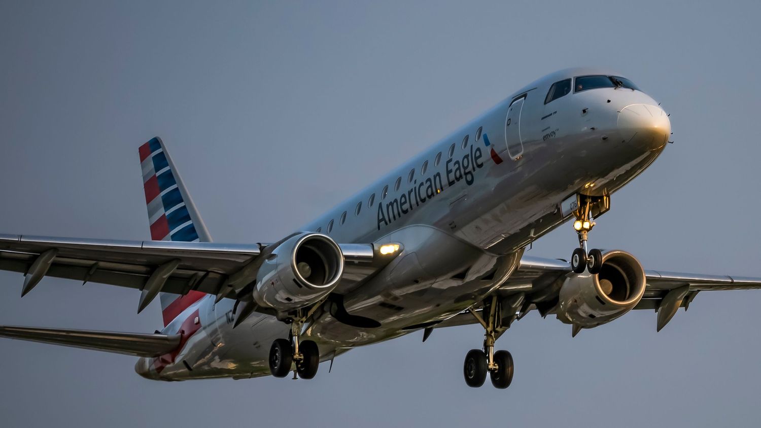 American Eagle Embraer ERJ-175 regional jet aircraft on final approach with landing gear deployed.