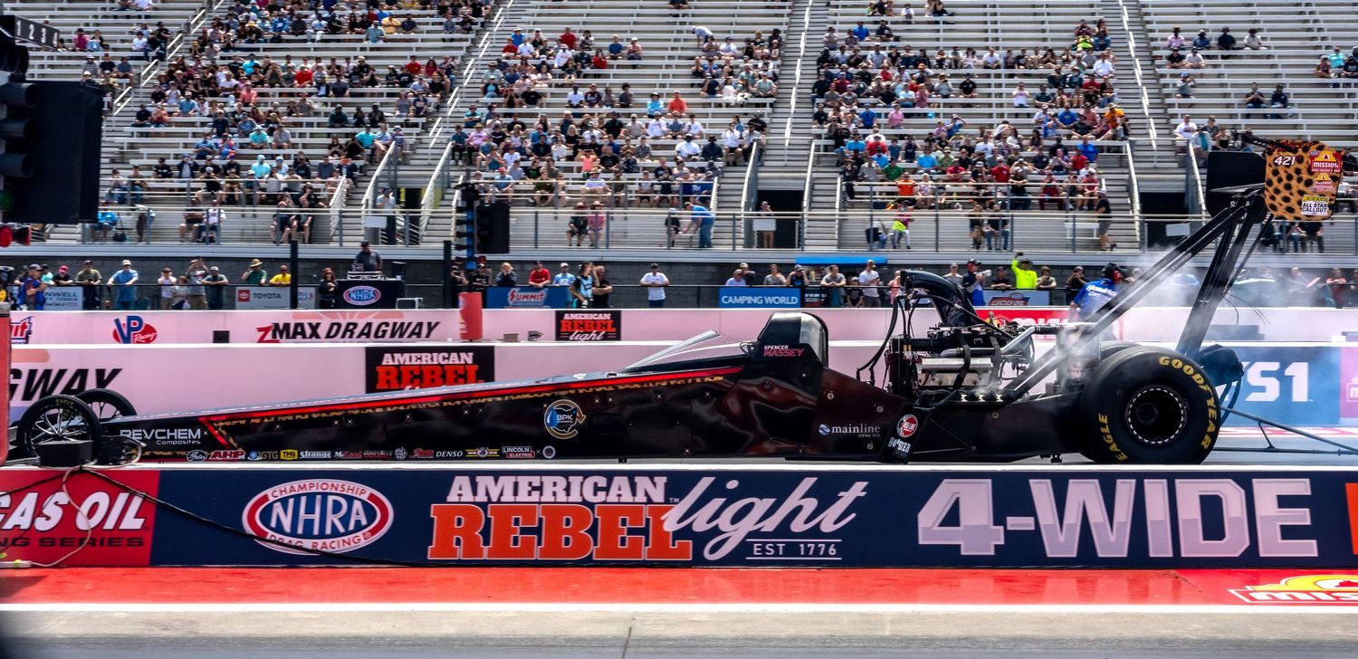 Panoramic view of a crowded drag racing event with spectators in the grandstands.