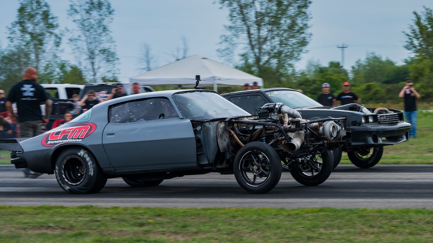 Modified sports cars performing synchronized drifting maneuvers at a track event.