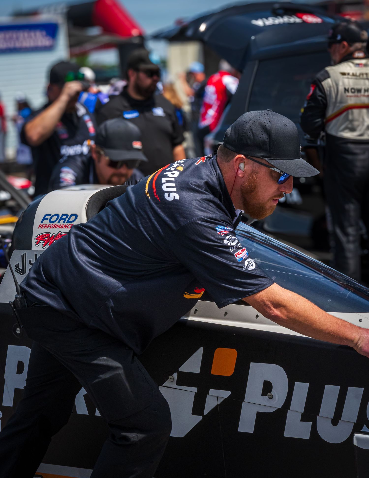 A crew member working on a race car in the pit area during an event.