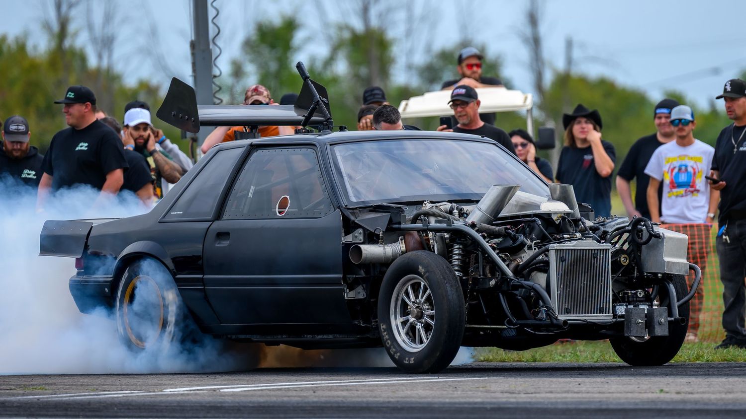 Drag racing action shot showing multiple cars competing on the track.