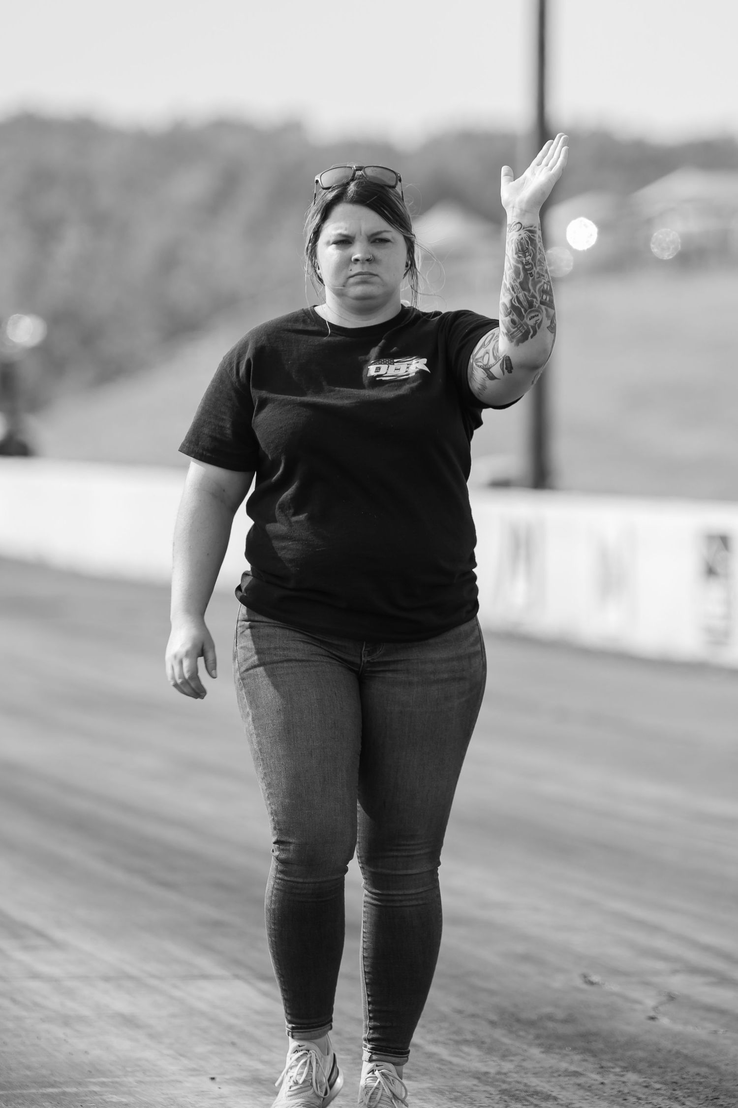 A sequence of black and white photos showing someone walking across a drag racing track surface.