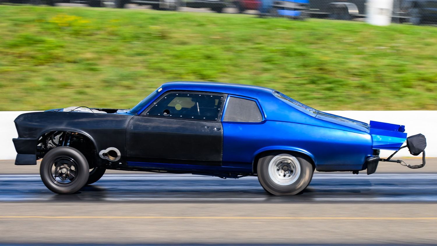 High-speed drag racing cars photographed in motion on a sunny race day.