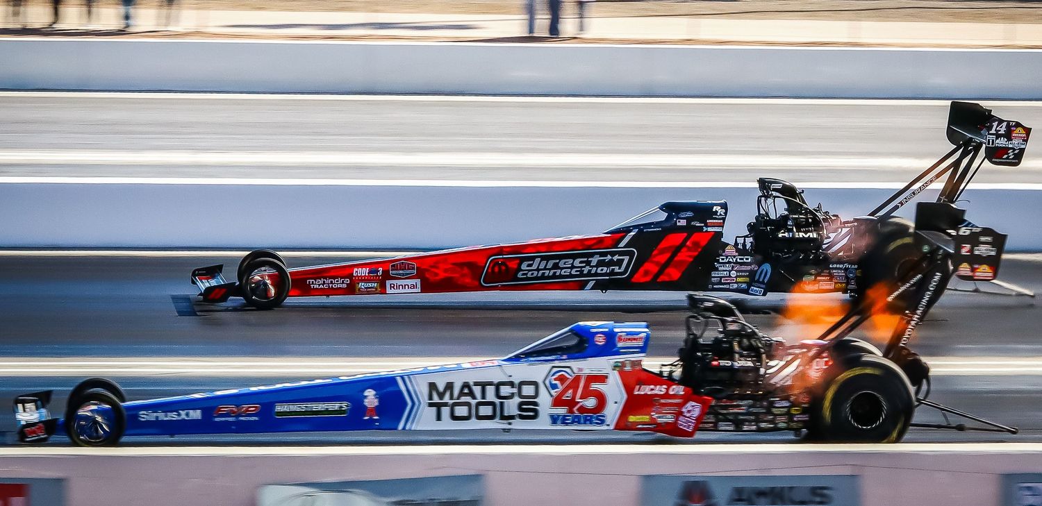Multiple drag racing cars lined up on track during competitive racing event.