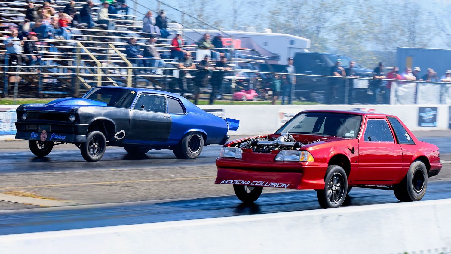 Multiple drag racing cars line up on a track during a racing event.